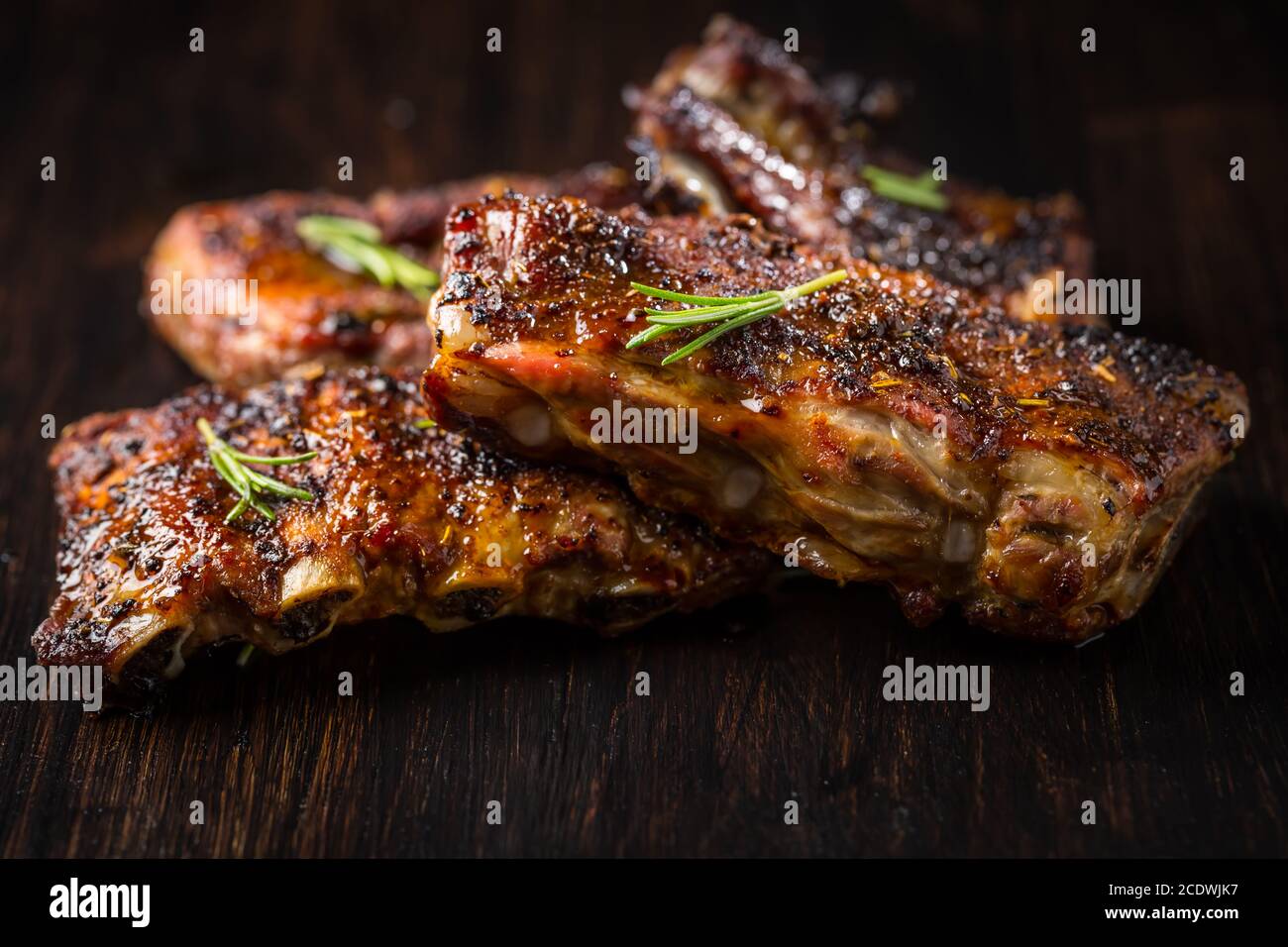 Gegrillte Schweinebrippen mit Rosmarin auf Holzhintergrund. Konzept für Grillgerichte. Stockfoto