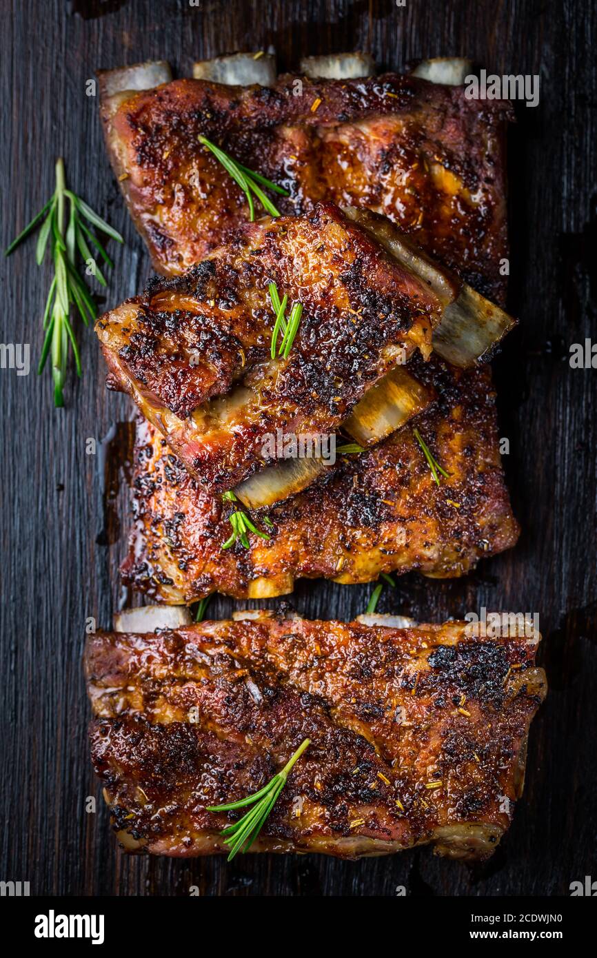 Gegrillte Schweinebrippen mit Rosmarin auf Holzhintergrund. Konzept für Grillgerichte. Stockfoto