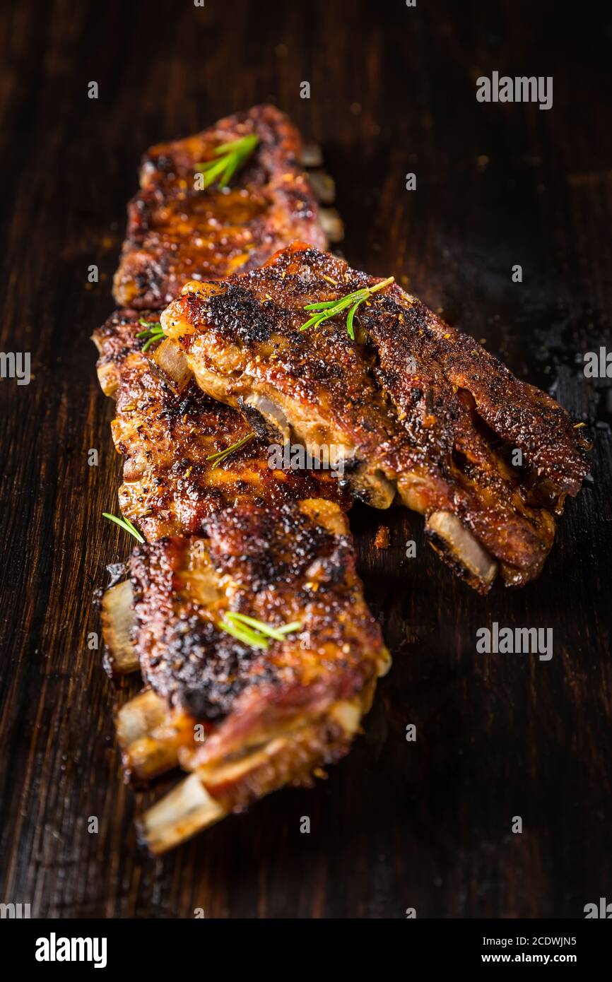 Gegrillte Schweinebrippen mit Rosmarin auf Holzhintergrund. Konzept für Grillgerichte. Stockfoto