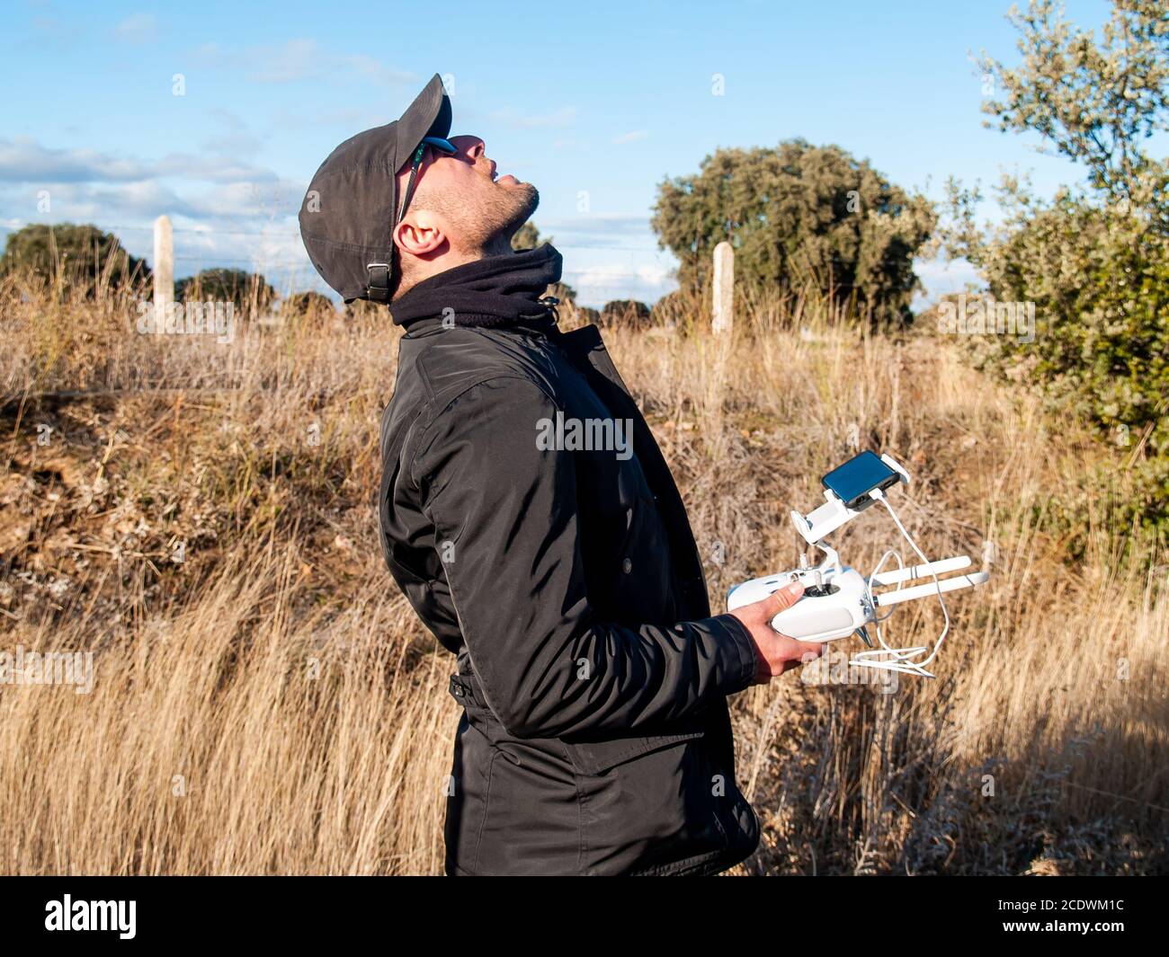 Ein Drohnenpilot, der mit der Fernbedienung mit dem Smartphone pilotieren kann In seinen Händen im Wald und schaut Stockfoto