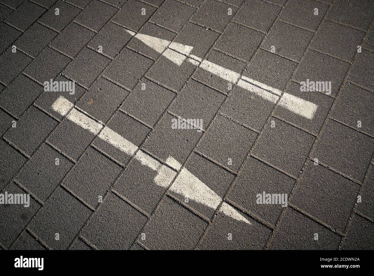 Richtungspfeile auf einer gepflasterten Straße Stockfoto