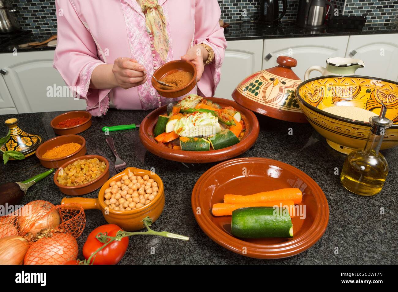 Hände einer Frau, die einem traditionellen Marokkaner Gewürze zufügt Tajine während der Ramadan-Nächte (Marokkanische Immigrantin in der modernen europäischen Küche) Stockfoto