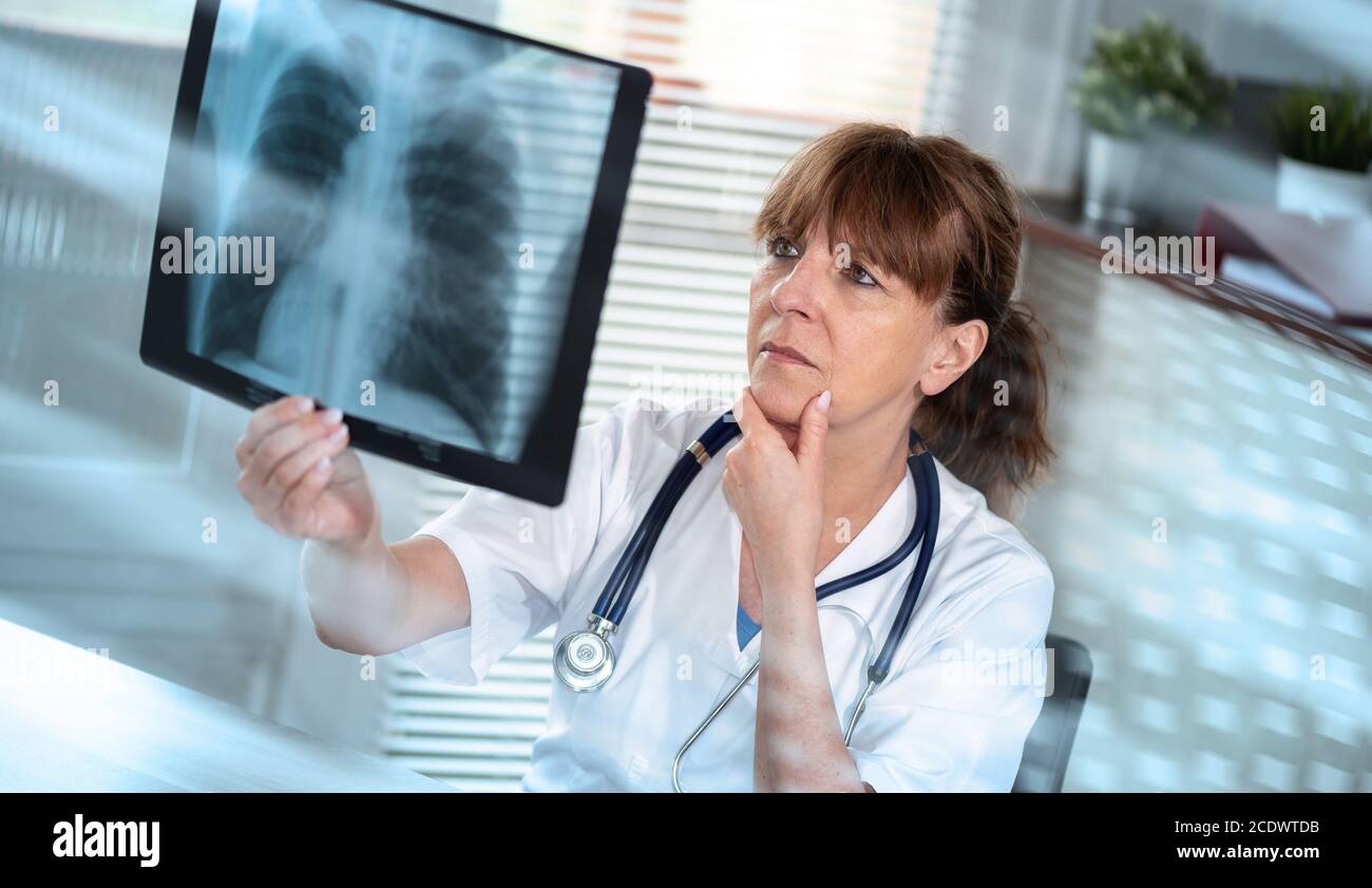 Ärztin, die Röntgenbericht in der Arztpraxis untersucht; Lichteffekt Stockfoto
