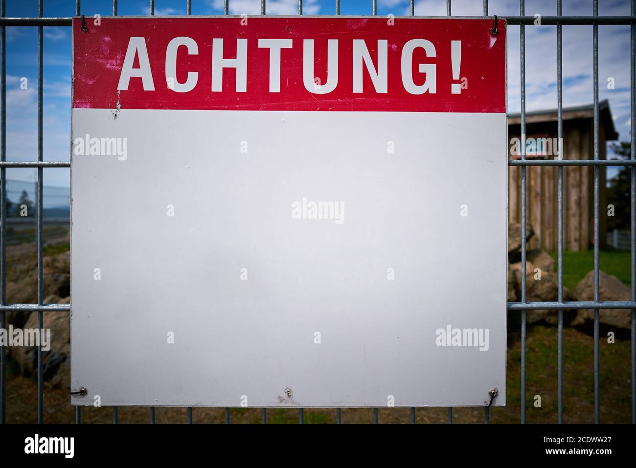 Schild mit der Aufschrift Achtung auf einem Zaun Stockfoto