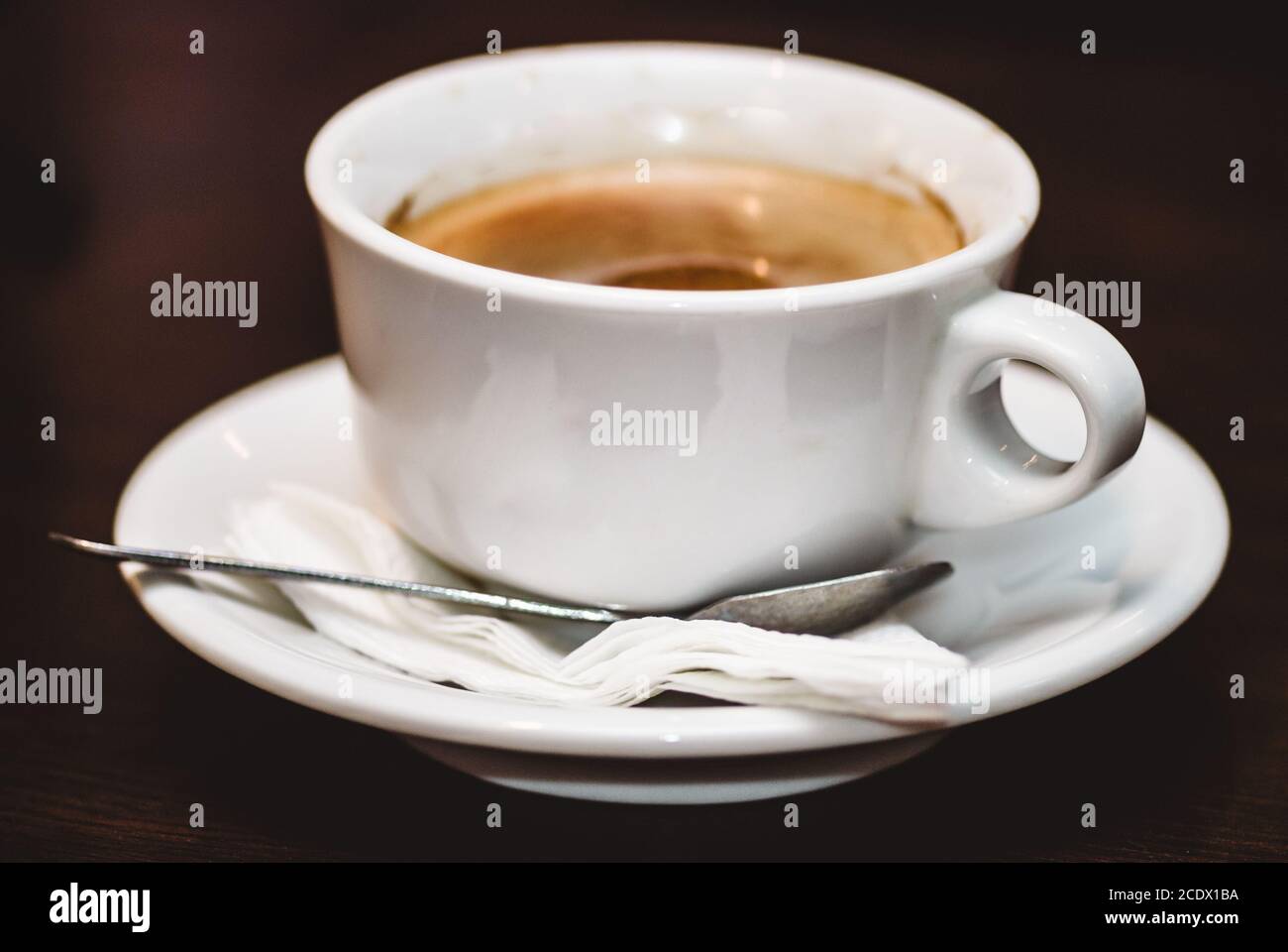 Nahaufnahme einer Tasse starken, schaumigen Espresso auf einer rauhen, braunen Holzoberfläche. Selektiver Fokus Makroaufnahme mit Stockfoto