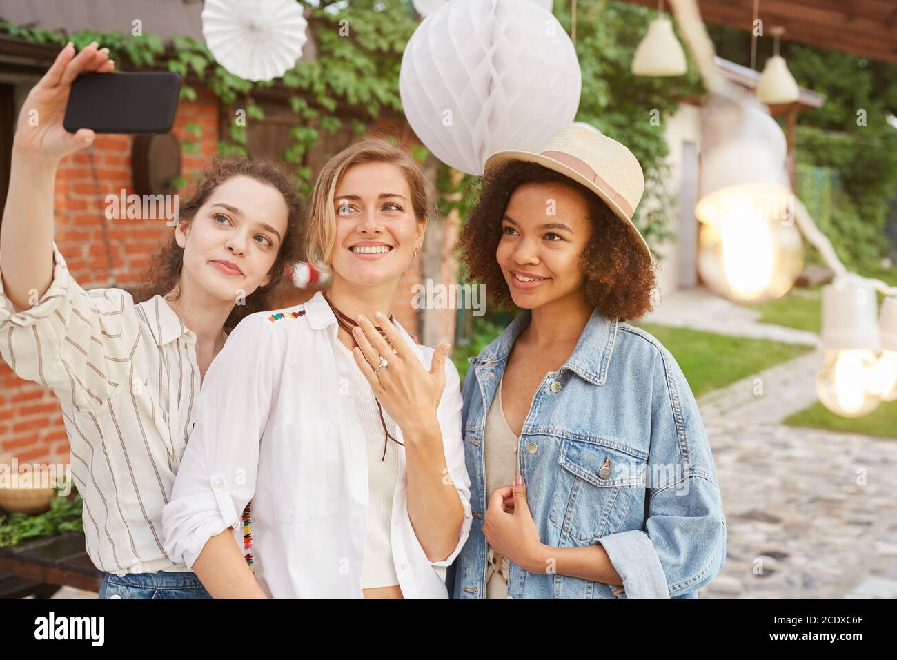Taille up Porträt der schönen jungen Frau zeigt Verlobungsring Selfie mit Freunden während der Party im Freien, kopieren Raum Stockfoto