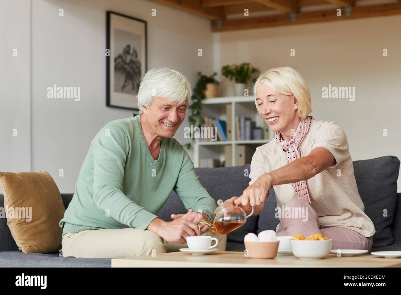 Seniorenpaar sitzt auf dem Sofa und trinkt gemeinsam Tee Das Wohnzimmer Stockfoto