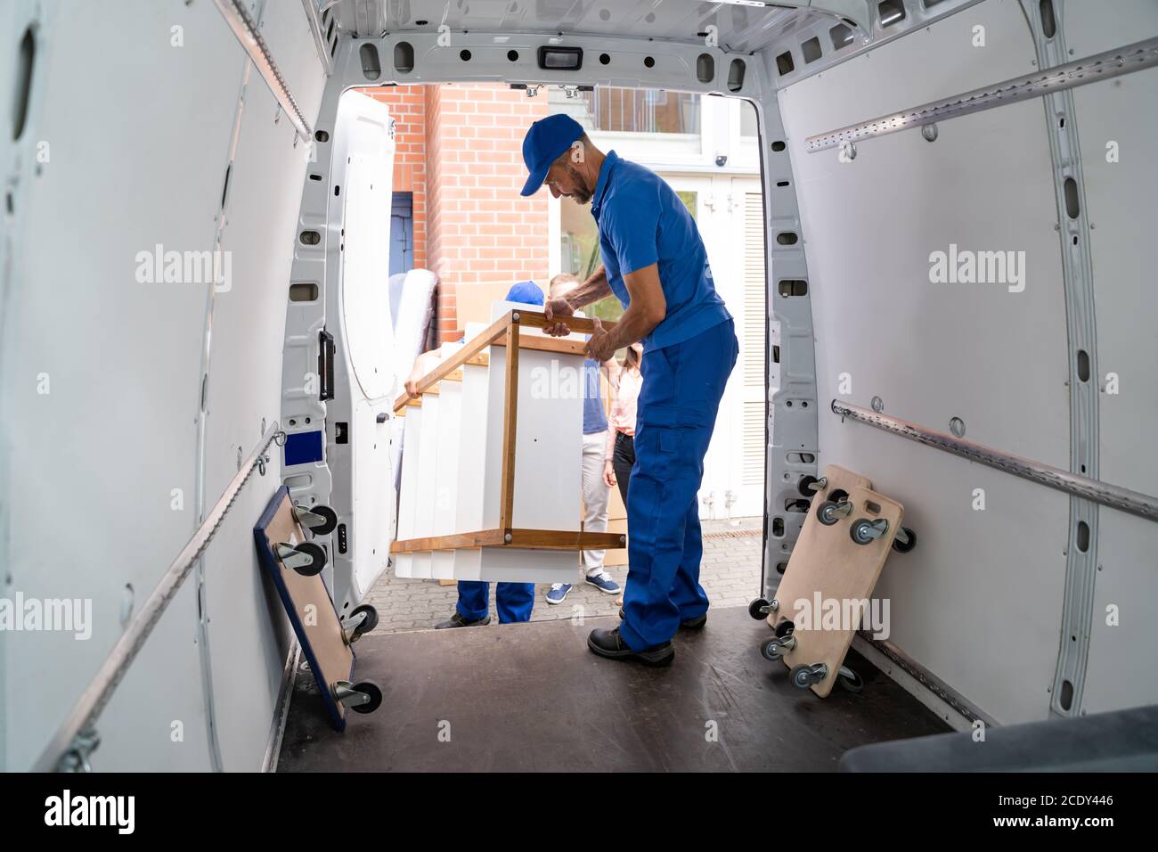 Glückliche Familie Paar Beobachten Movers Entladen Möbel Aus Lkw Stockfoto