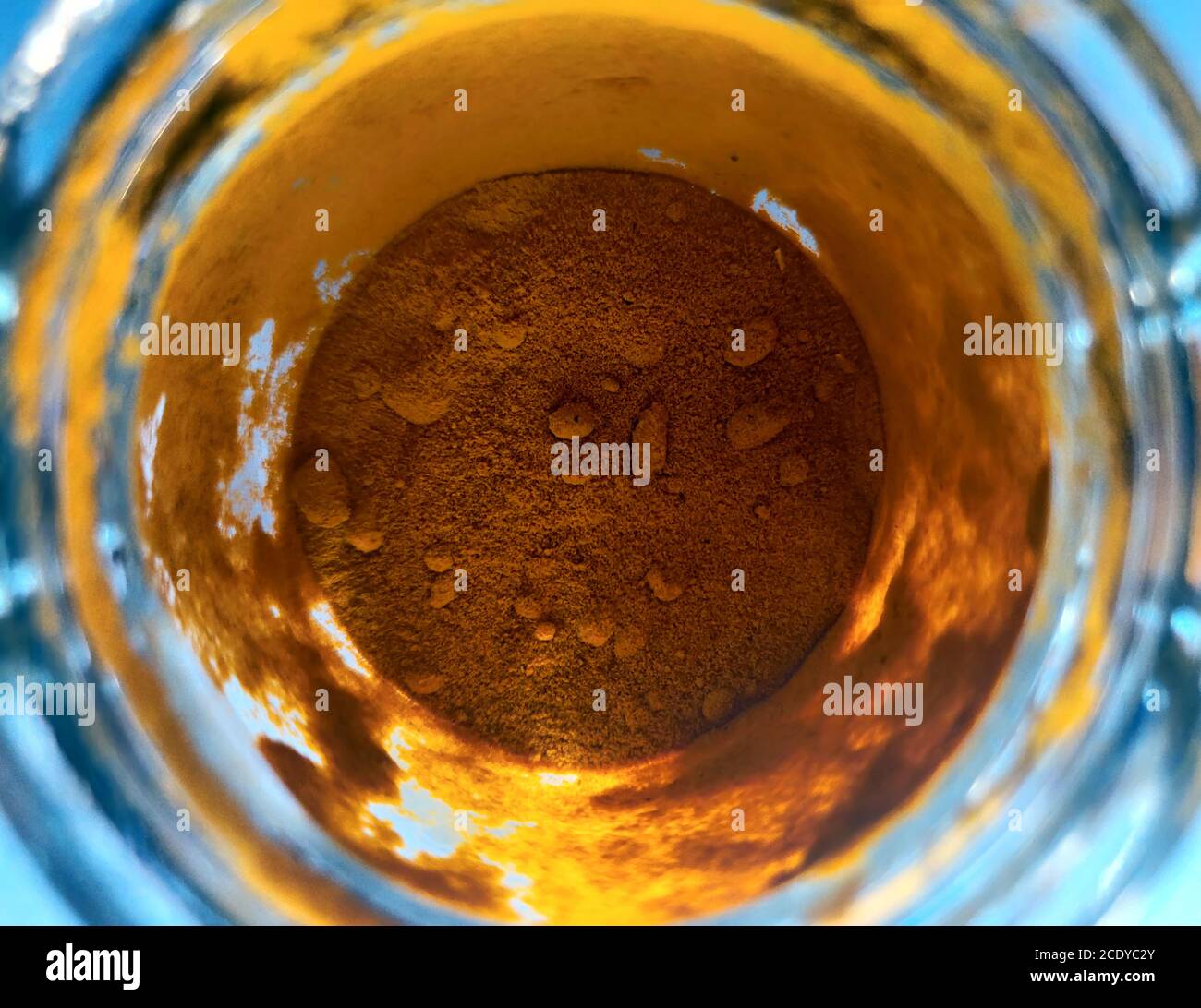 Orange Kurkuma Pulver in Glas Tasse, Schüssel mit Zutat close up. Farbige Granulat in transparenten Behälter. Magisches Fantasiepuder. Alchemie und Eleme Stockfoto