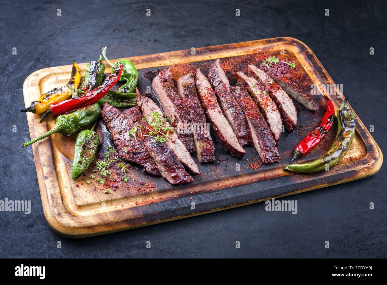 Traditionelle Grill in Scheiben geschnitten trocken gealterte Wagyu Flanke Steak mit angeboten Chili und Paprika als Nahaufnahme auf einem rustikalen verbrannten Holz cuttin Stockfoto