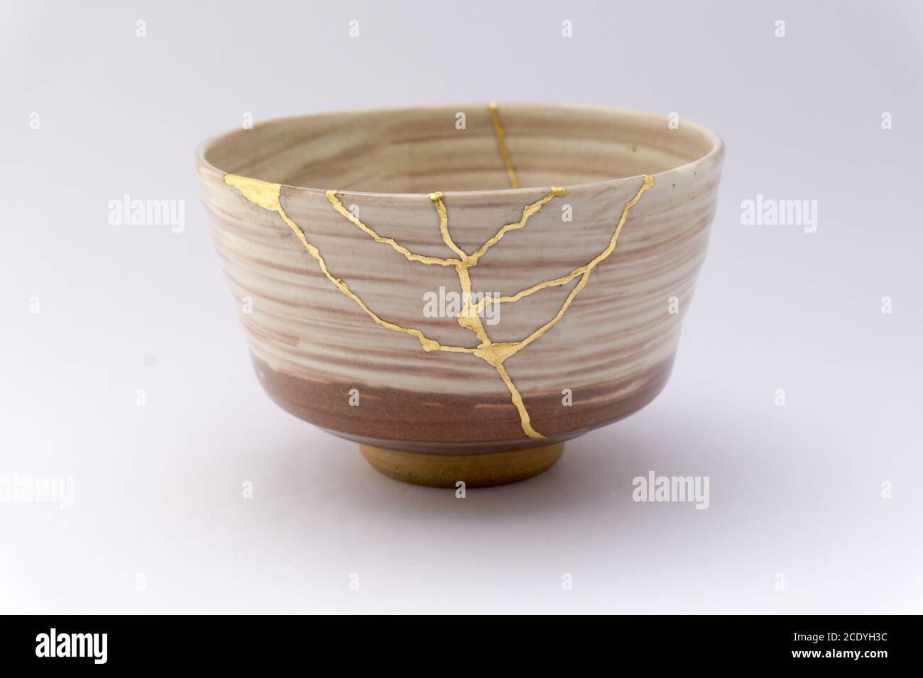 Kintsugi beige Chawan. Goldene Risse reparieren auf alten japanischen Keramik. Stockfoto