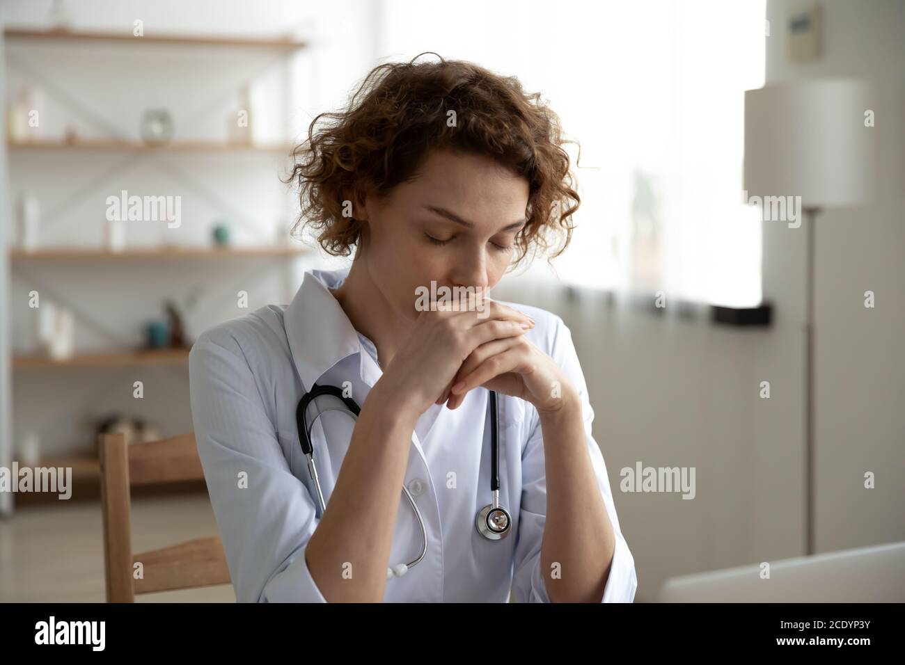 Nahaufnahme nachdenkliche Frau Arzt sitzt am Schreibtisch Stockfoto