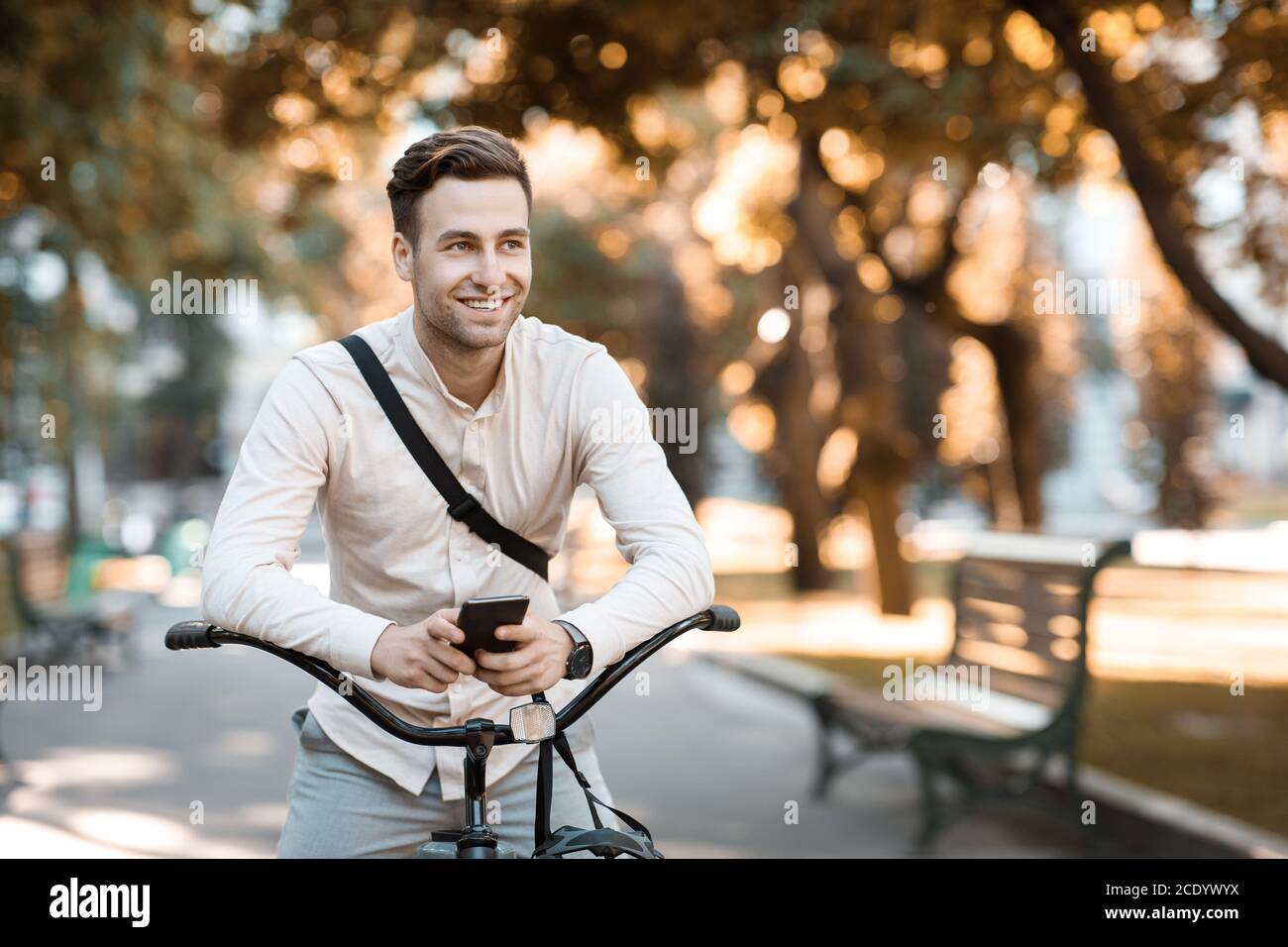 Straßenstil. Junge stilvolle Mann SMS auf Telefon, während auf dem Fahrrad sitzen Stockfoto