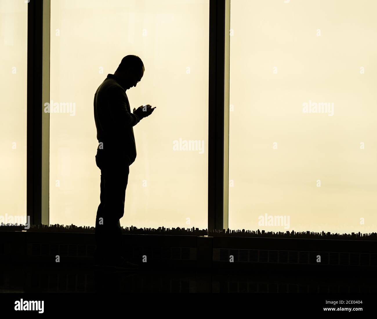 Mann, der mit dem Smartphone im Fenster herumspielt Stockfoto
