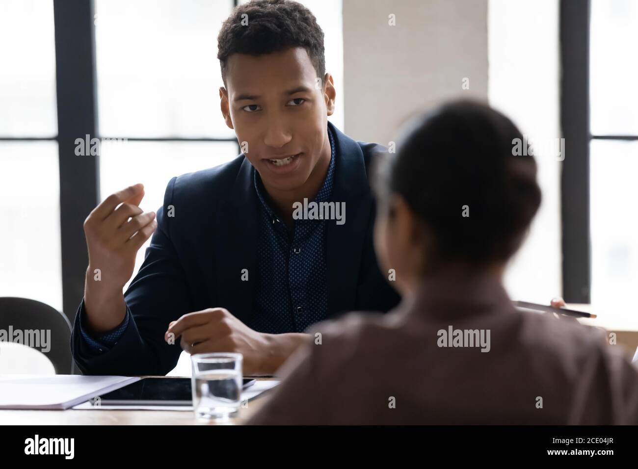 Junge afroamerikanische Managerin, die Projektideen mit indischen Kollegen teilt. Stockfoto