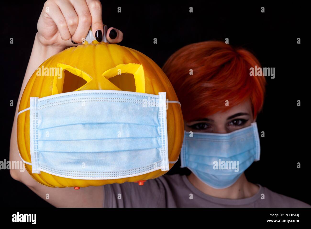 Mädchen mit Kürbis mit Gesichtsmaske - halloween in der Alter des Coronavirus Stockfoto
