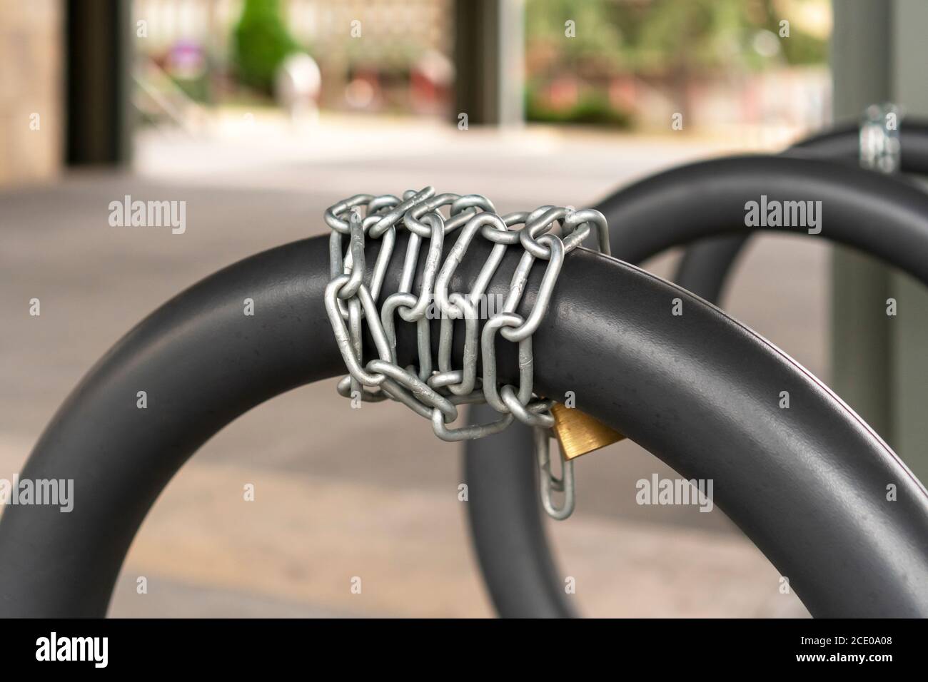 Kettenschloss für Fahrradsicherheit im Fahrradparkplatz mit grauen Eisenringen. Lifestyle- und Sicherheitskonzept Stockfoto