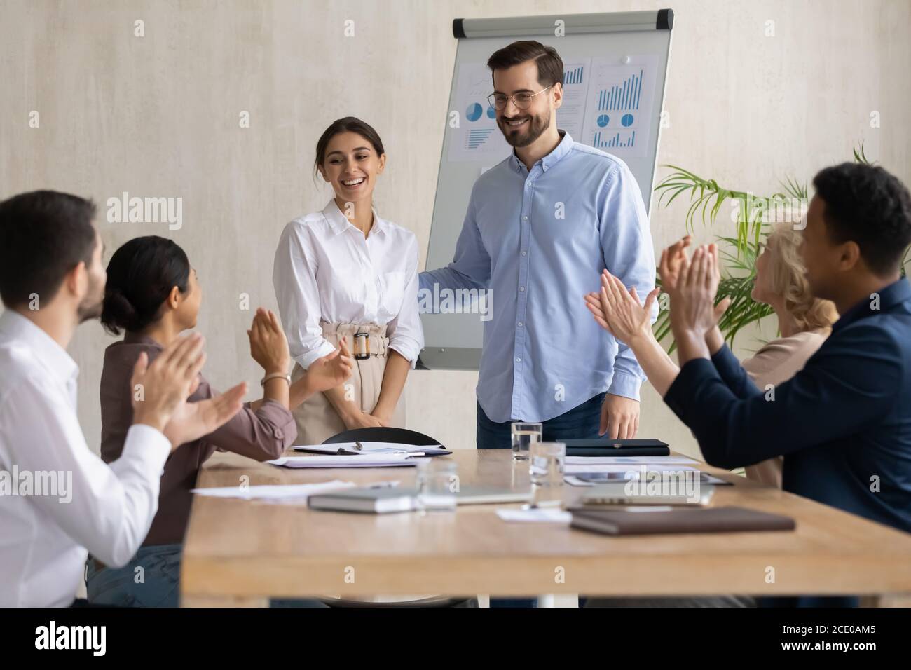 Lächelnde Kollegen applaudieren arabischen Kollegen. Stockfoto