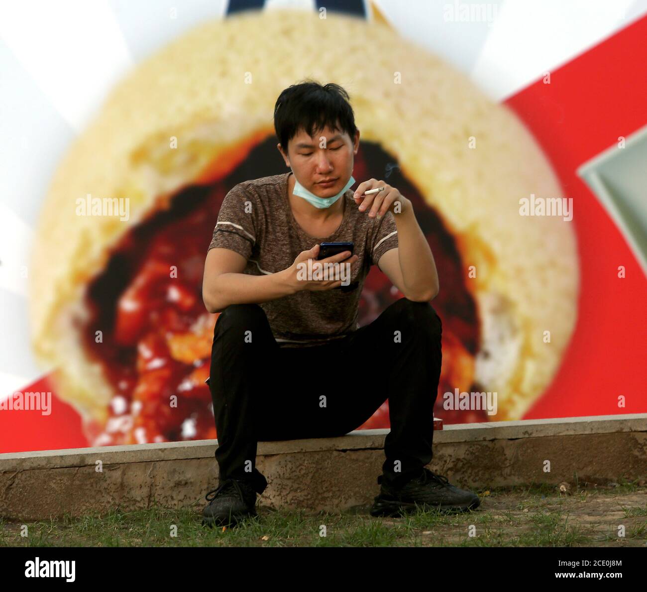 Peking, China. August 2020. Ein chinesischer Kellner mit Gesichtsmaske macht am Sonntag, den 30. August 2020, vor einem Knödelrestaurant in Peking eine Rauchpause. Obwohl Chinas Hauptstadt das obligatorische Tragen von Gesichtsmasken im Freien aufgehoben hat, schützen sich viele Chinesen aufgrund der möglichen Rückkehr des Coronavirus weiterhin. Laut US-Geheimdiensten hielten Beamte in Wuhan Peking wochenlang im Dunkeln über die mögliche Verwüstung des Coronavirus. Foto von Stephen Shaver/UPI Kredit: UPI/Alamy Live Nachrichten Stockfoto