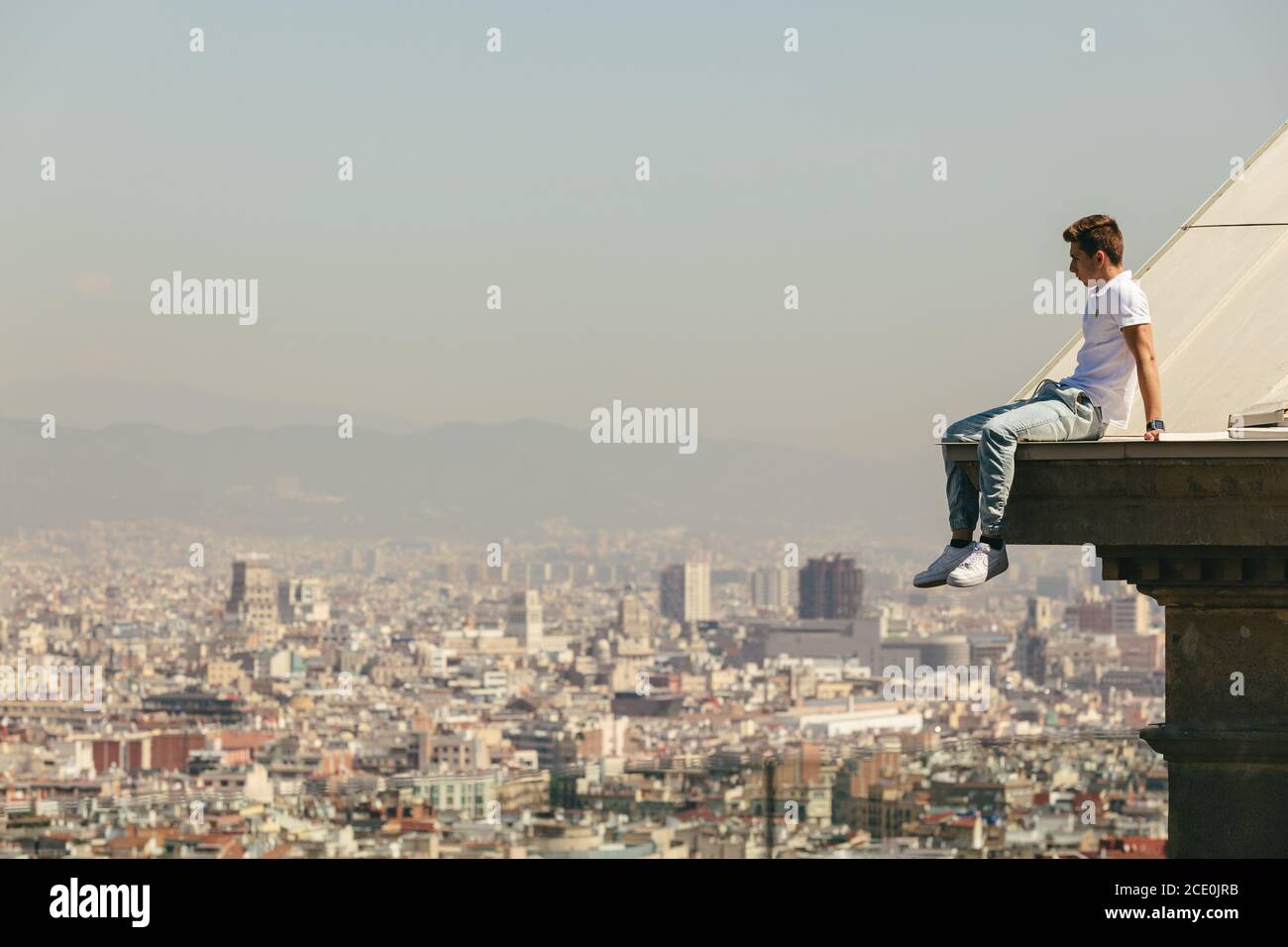 Ein Junge sitzt, während er Barcelona vom nationalen Kunstmuseum Kataloniens aus betrachtet Stockfoto