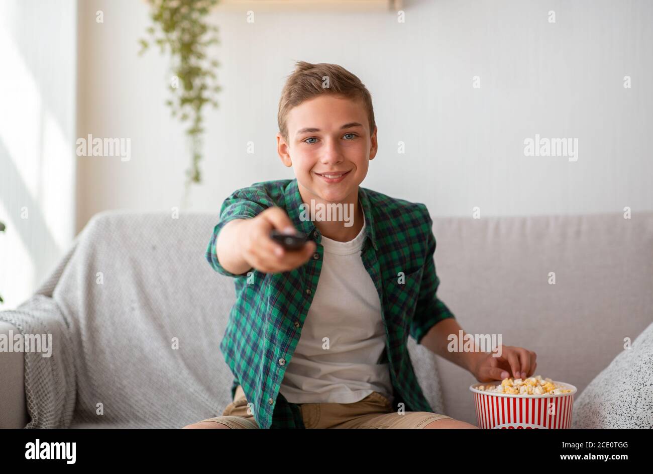 Schuljunge, der Popcorn isst, während er Fernsehen schaut Stockfoto
