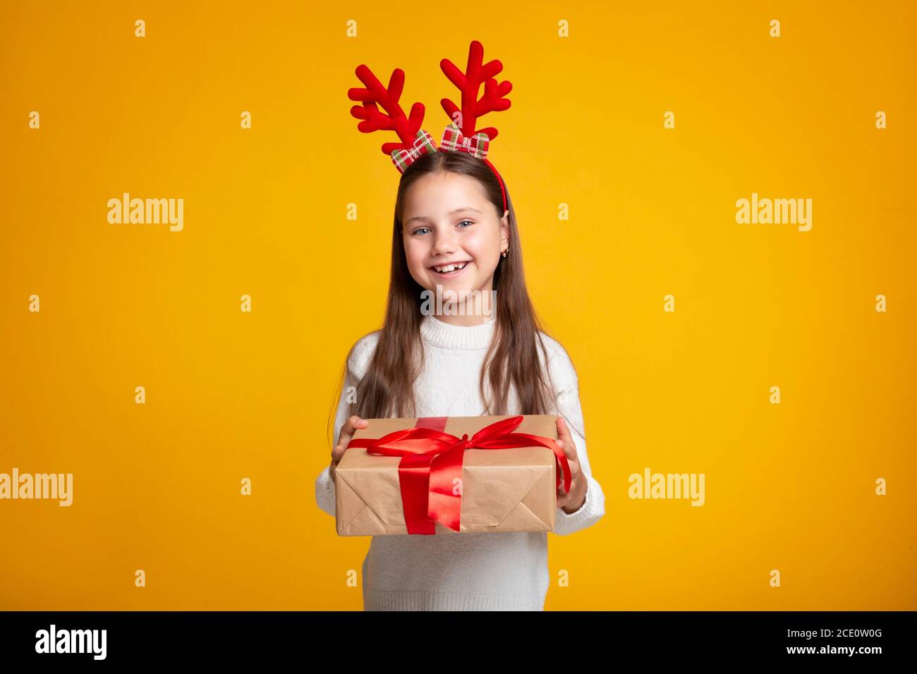 Emotionen des Glücks von Weihnachten. Lächelndes kleines Kind mit Hörnern im Pullover mit Geschenk Stockfoto
