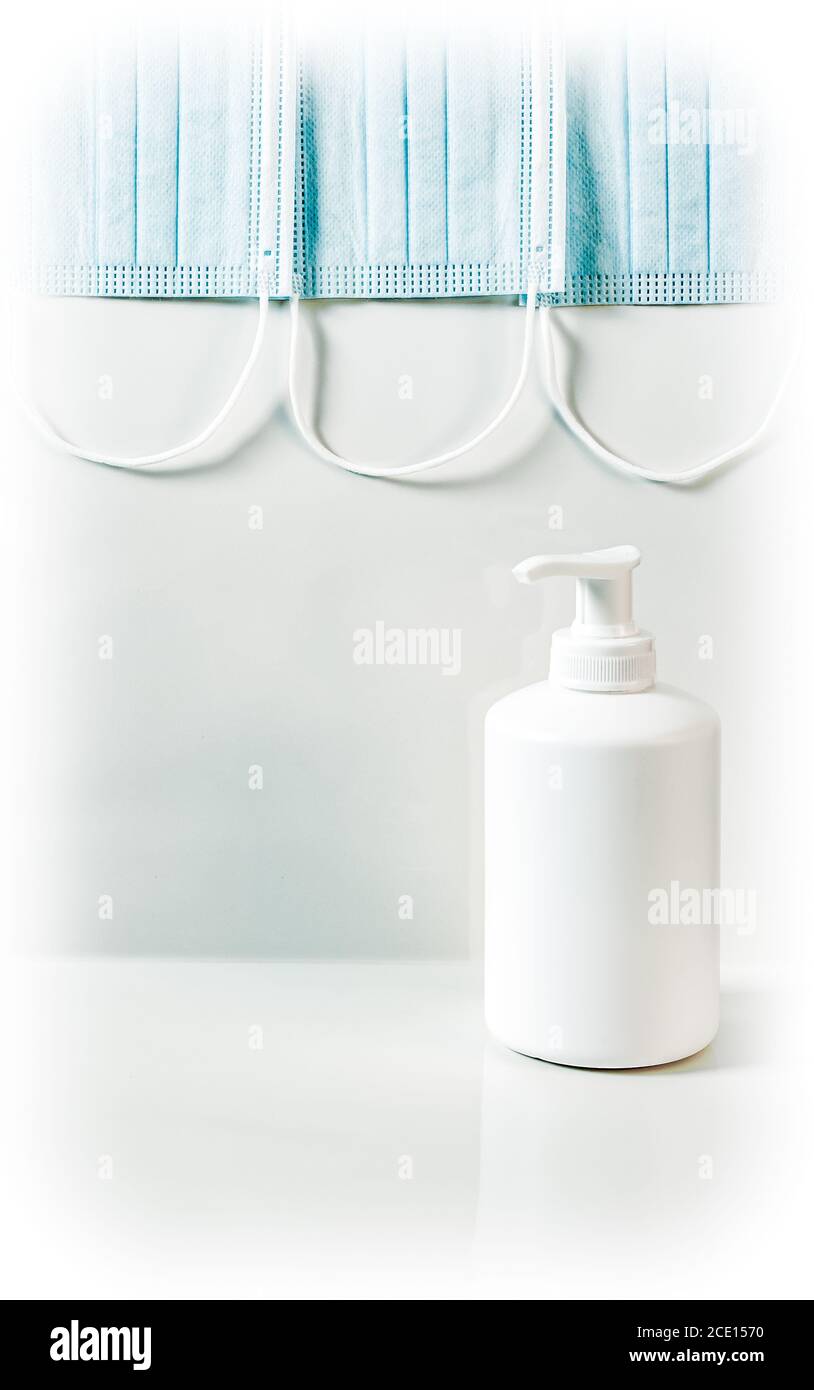 Coronavirus-Präventionskonzept. Blaue medizinische Maske und weiße Kunststoff-Pumpe Flasche Hand Desinfektionsmittel Gel oder Seifenspender. Stockfoto