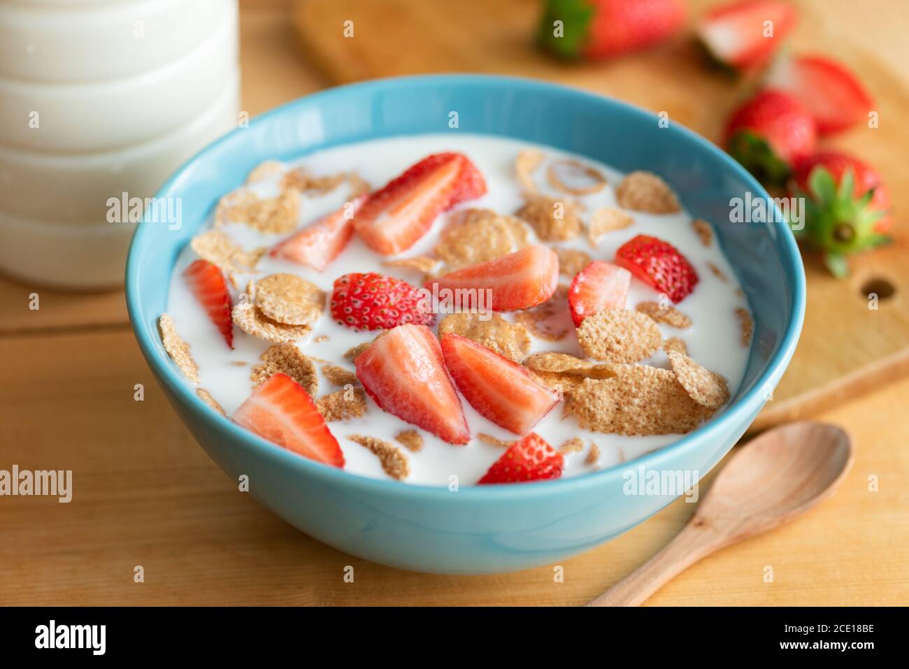 Vollkornflocken mit Milch und Erdbeeren in einer Schüssel auf Holztisch. Gesundes, nahrhaftes Frühstück Stockfoto
