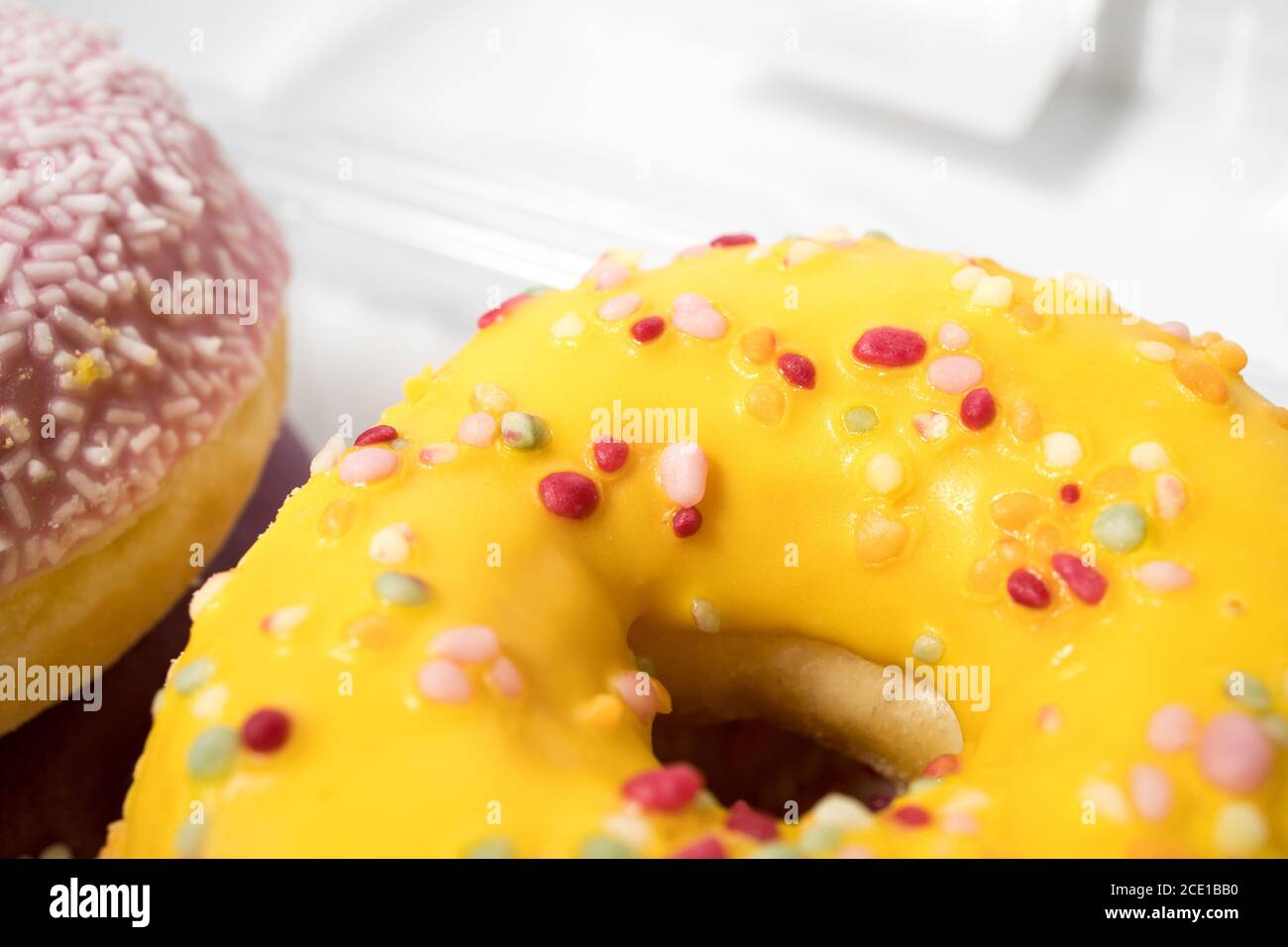 Nahaufnahme eines köstlichen glasierten Bananengeschmack Donuts in einer Box auf weißem Hintergrund. Stockfoto