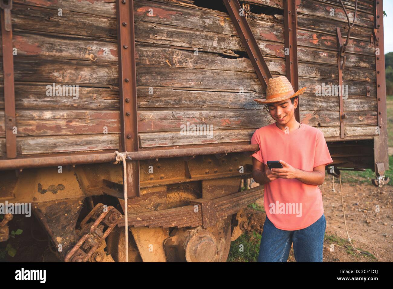 Junger Mann mit Jeans und einem Cowboy Hut mit seinem Smartphone mit Freunden zu kommunizieren. Ranch Konzept Fotografie Stockfoto