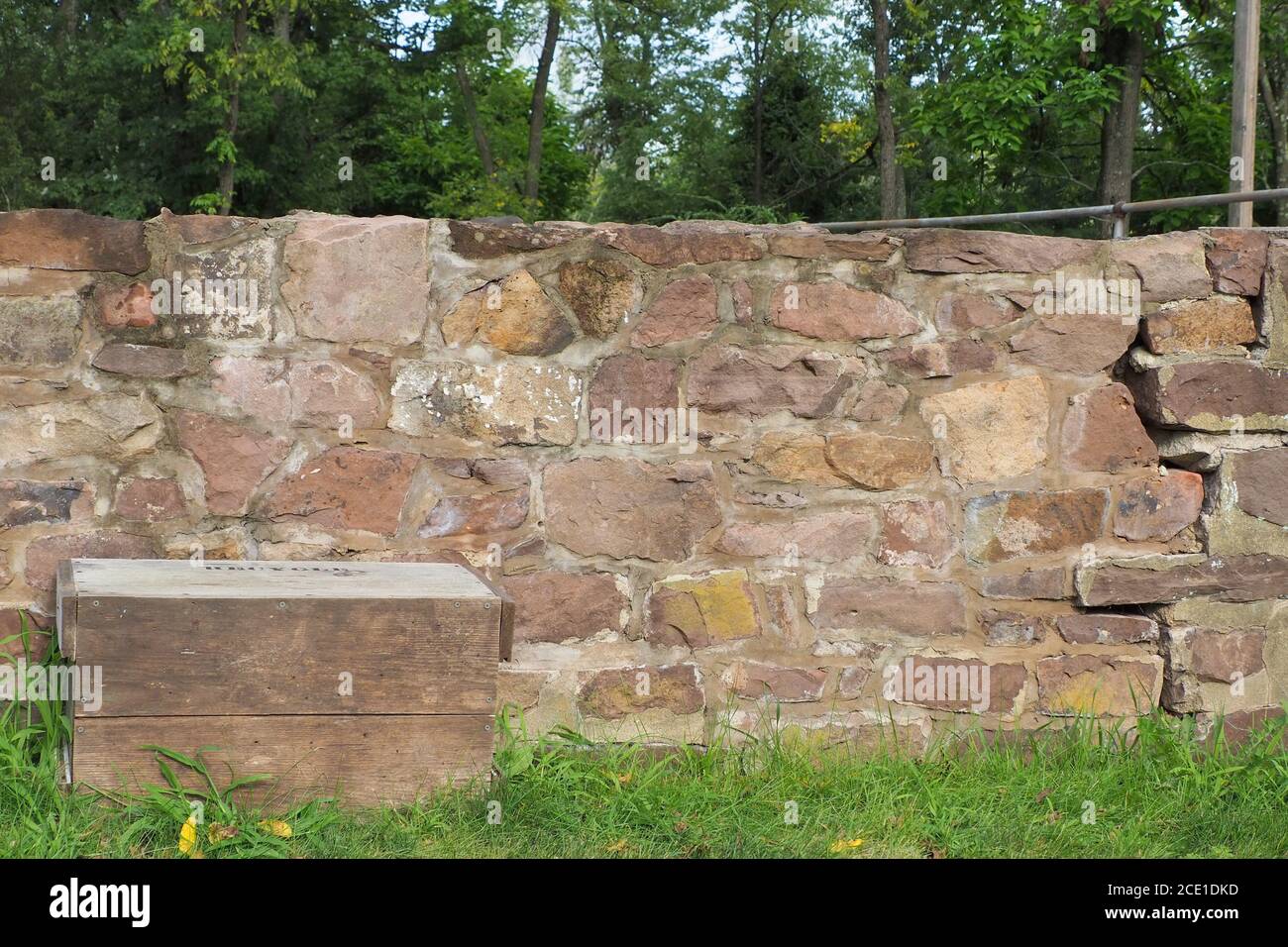 Die alte Steinmauer hat einen großen Riss im Fundament. Stockfoto