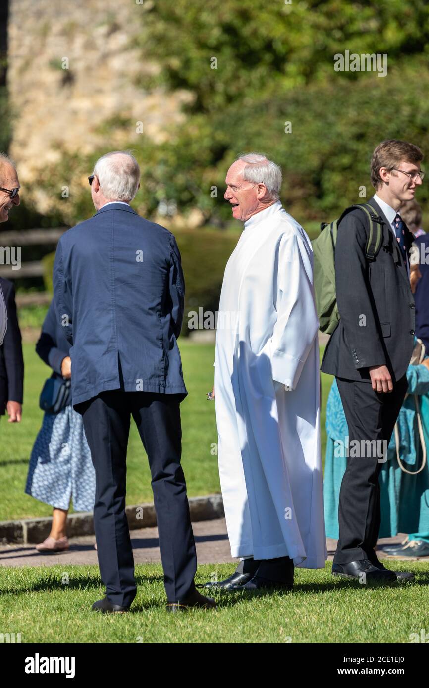Pfarrer in weißer Soutane im Gespräch mit Gemeindemitgliedern nach dem Sonntagsgottesdienst vor der Sherborne Abbey in Sherborne, Dorset, Großbritannien am 30. August 2020 Stockfoto