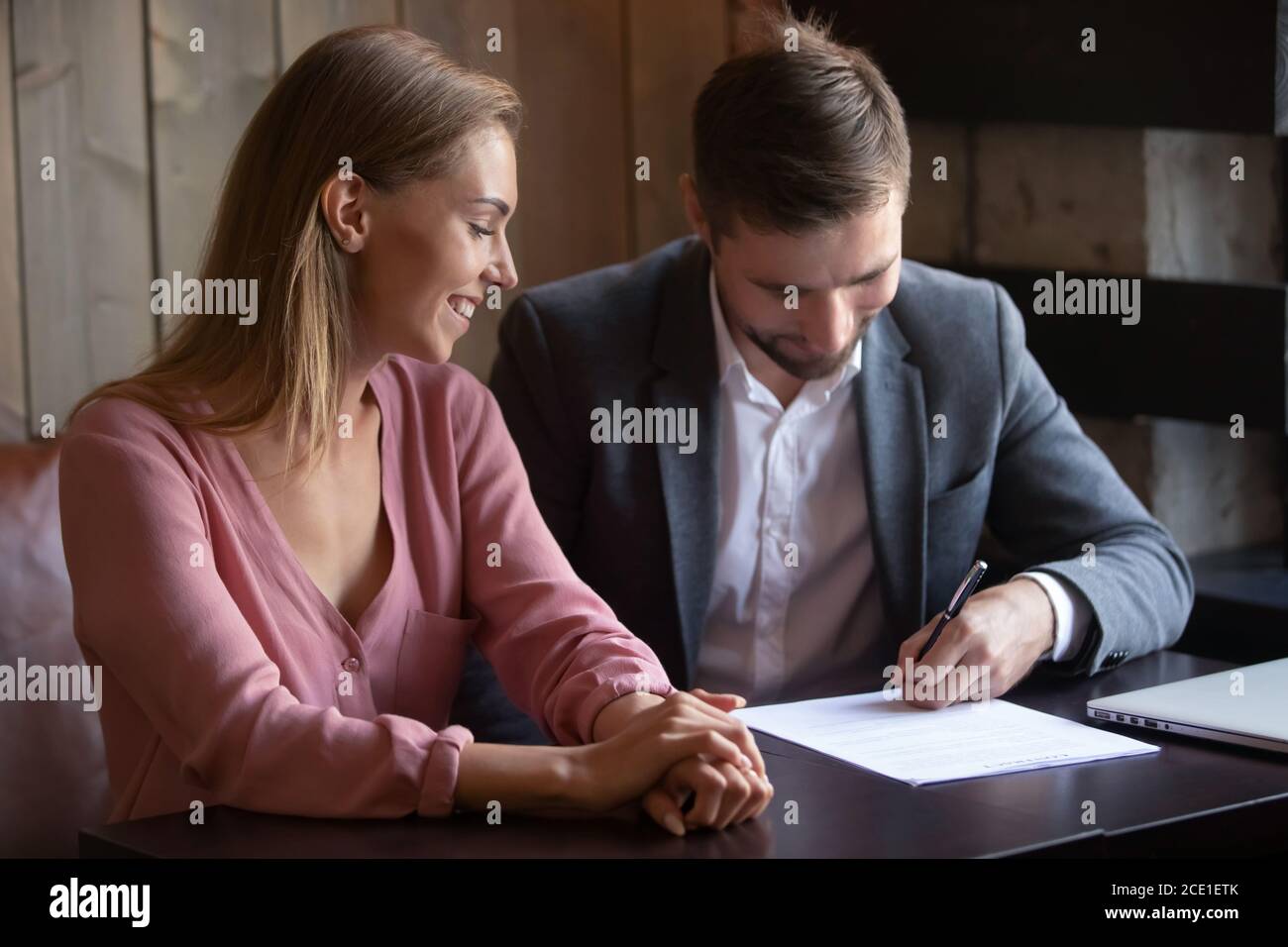 Zufriedene Frau und Mann machen Investitionsabkommen, Unterzeichnung Vertrag Stockfoto