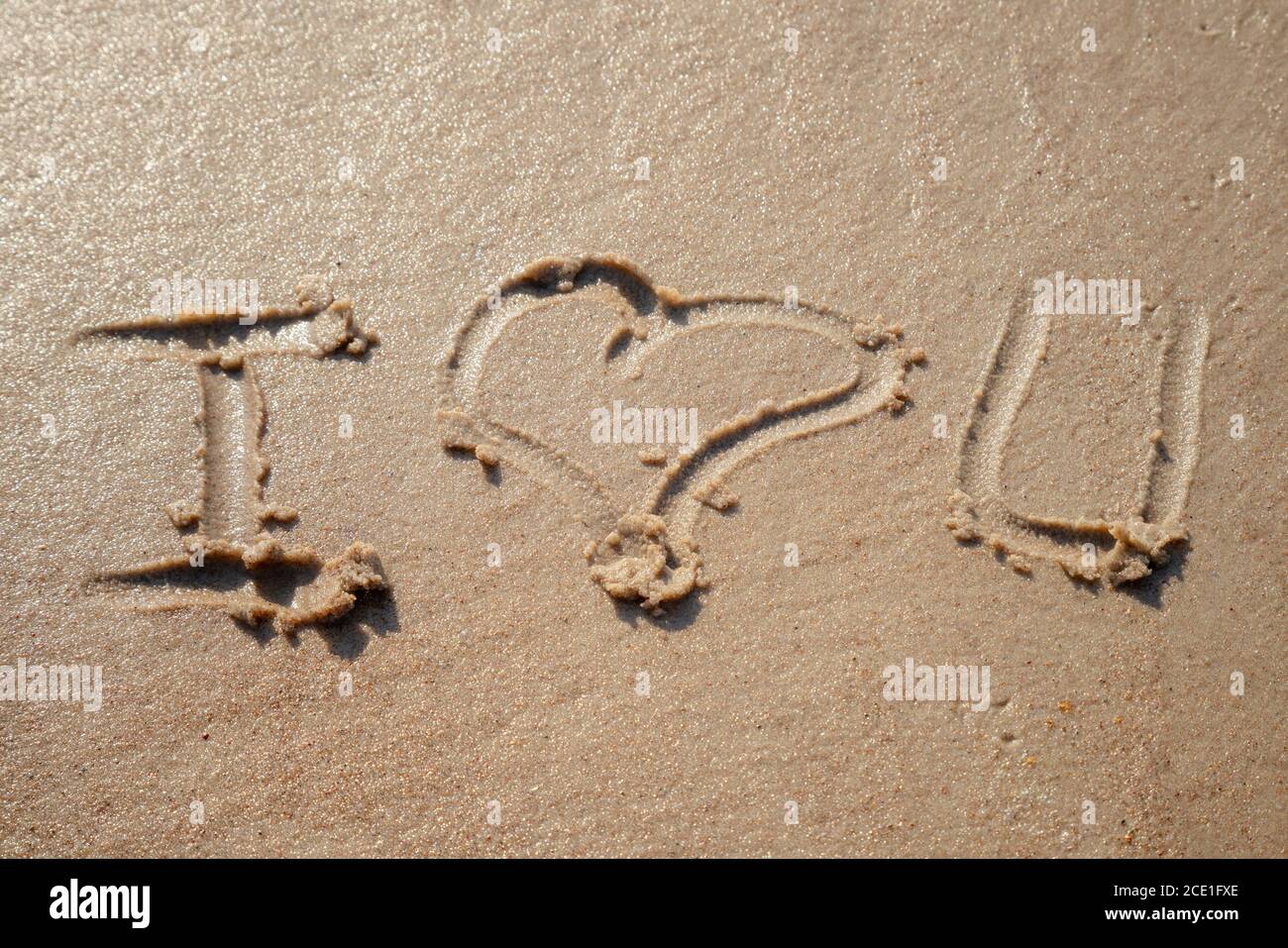 Ich liebe es, dass Sie am Strand auf dem Sand Zeichen weiß. Romantisches Liebessymbol an der tropischen Küste bei Sonnenuntergang. Stockfoto