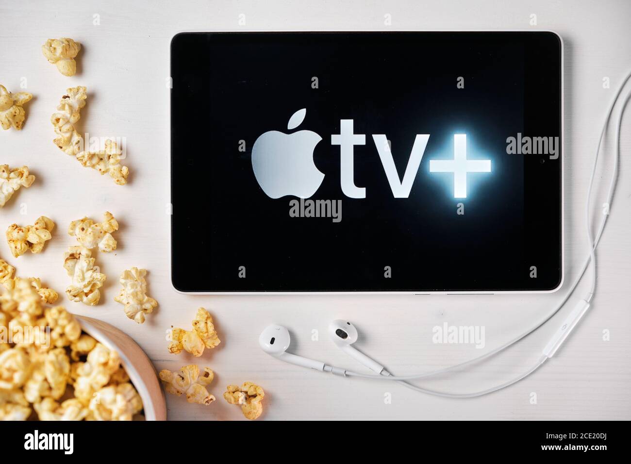 Apple tv plus Logo auf dem Bildschirm des Tablets, das auf dem weißen Tisch lag und darauf Popcorn streute. August 2020, San Francisco, USA Stockfoto