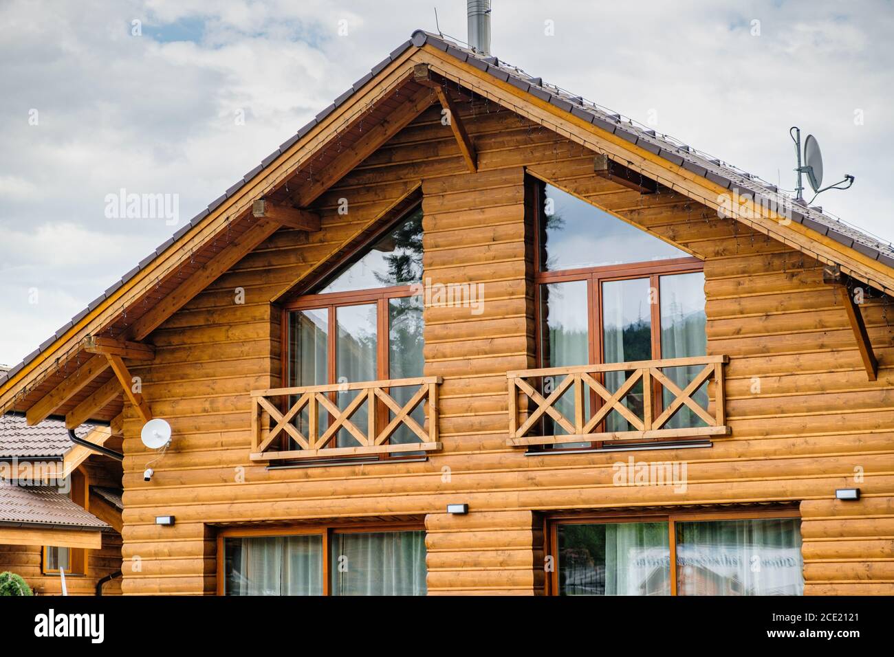 Modernes Holzhaus mit großen Fenstern und Balkon. Konzept des Baus von Familienhäusern, Pensionen oder Hütten auf dem Land. Bau von Häusern Stockfoto