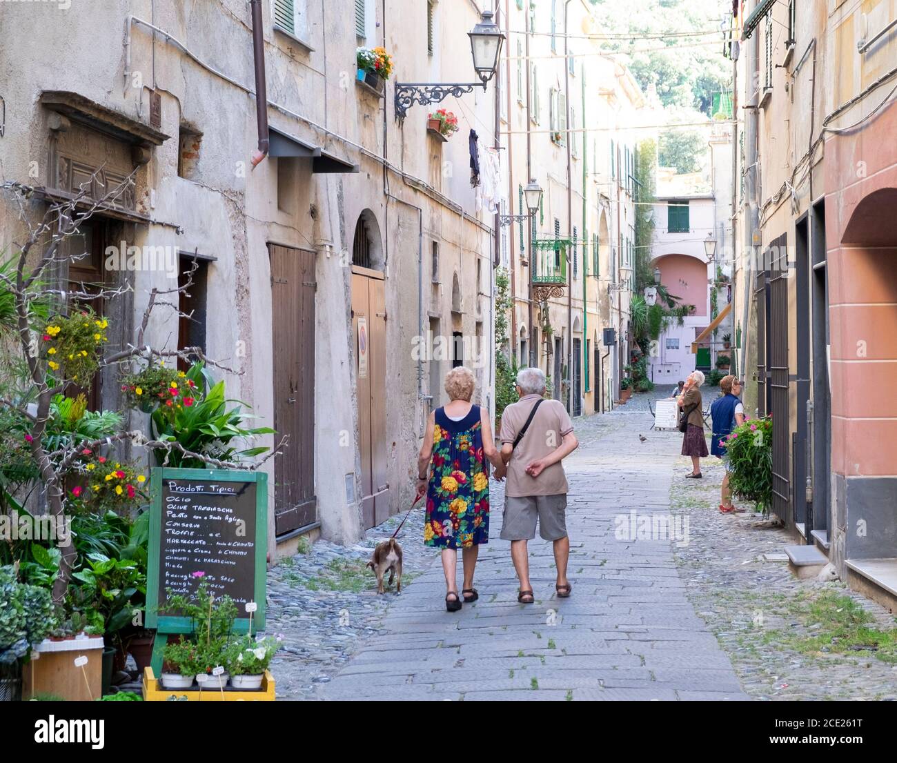 Ältere Paar zu Fuß mit ihrem Hund in der Altstadt von Finalborgo, Finale Ligure, Ligurien, Italien Stockfoto