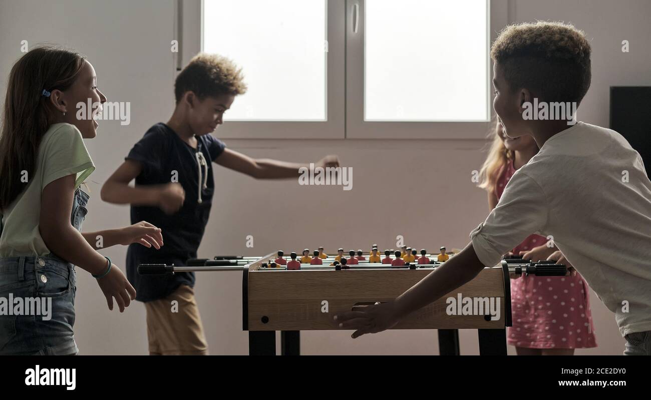 Gruppe von multikulturellen niedlichen Kinder stehen drinnen verbringen Spielzeit mit Freunden spielen Tischfußball zusammen. Tischversion von Fußballfans. Stockfoto