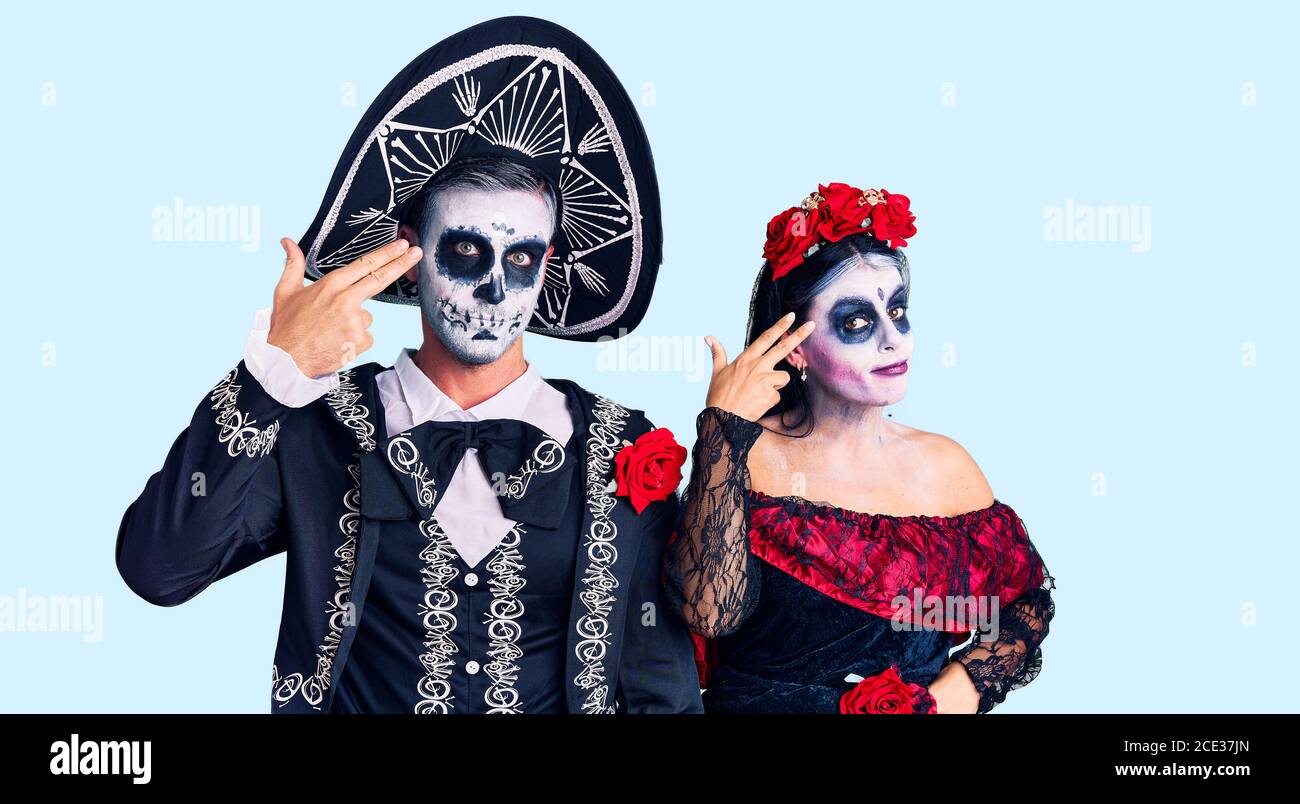 Junges Paar trägt mexikanische Tag der Toten Kostüm über Hintergrund  schießen und sich selbst töten Zeigen Hand und Finger an Kopf wie Waffe,  Selbstmord Stockfotografie - Alamy