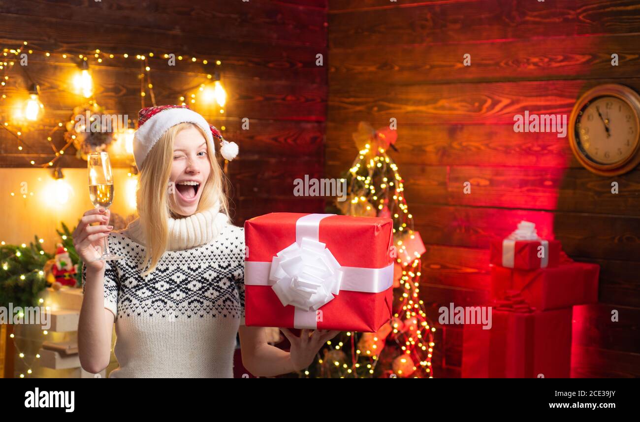 Santa Mädchen geben einen Augenzwinkern. Verrücktes komisches Gesicht. Weihnachtsdame wird in einem Weihnachtszimmer zwinkert. Neujahr. Stockfoto
