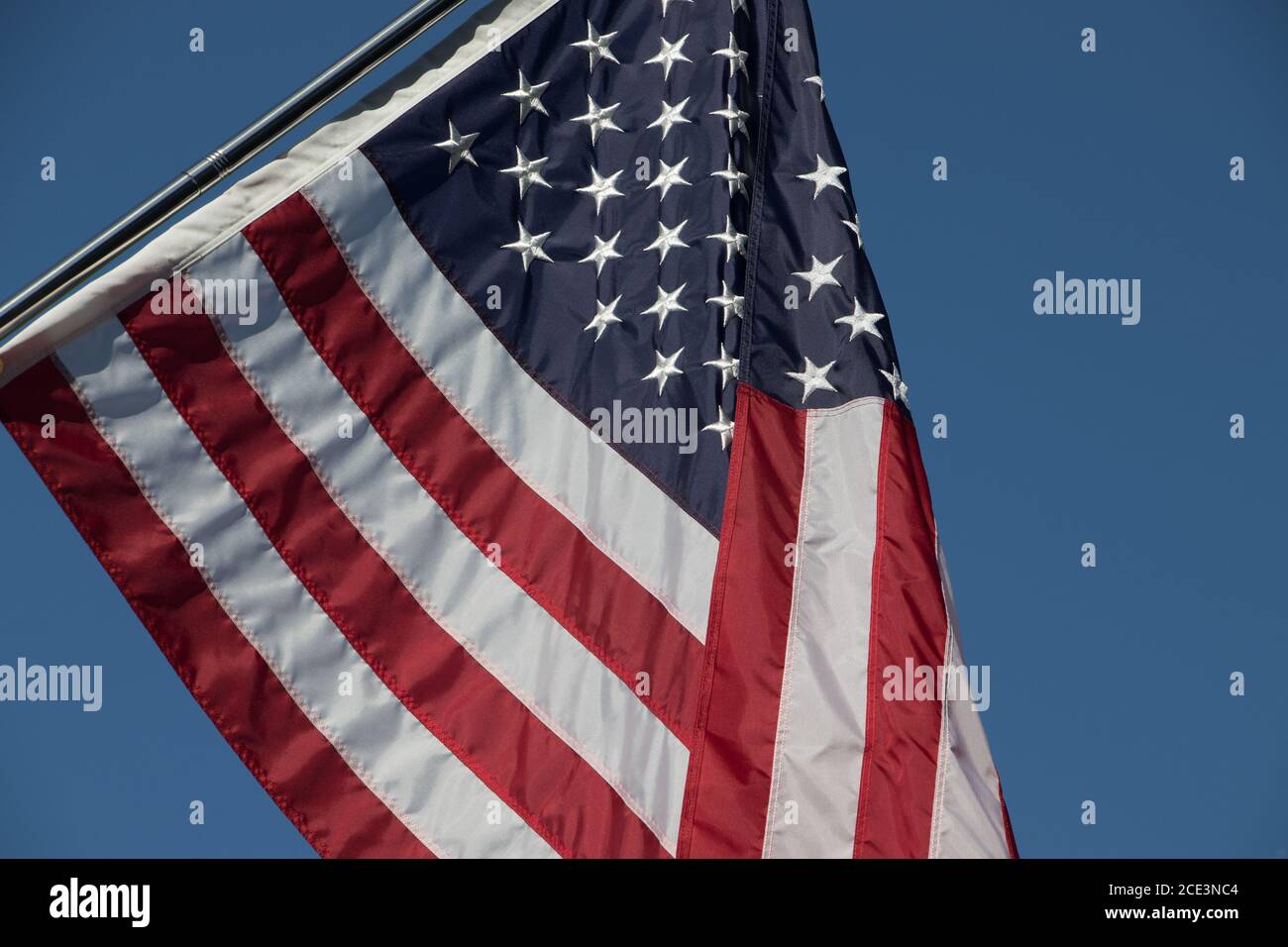Nahaufnahme der amerikanischen Flagge, die in der Brise mit fliegt Ein brillanter blauer Himmel Hintergrund Stockfoto