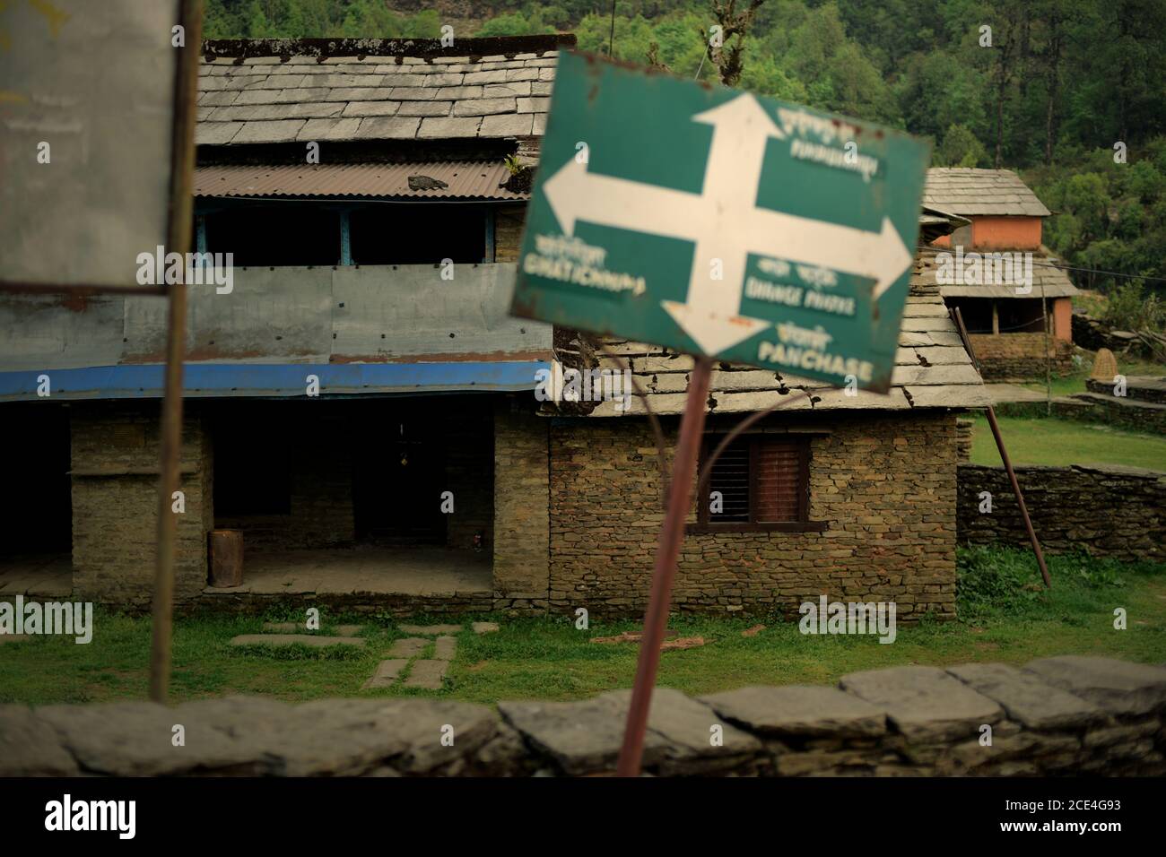 Wegweiser auf dem Landweg, vor einer leeren Pension im Ökotourismus-Dorf Bhanjyang, Panchase Bergregion, Nepal. Stockfoto