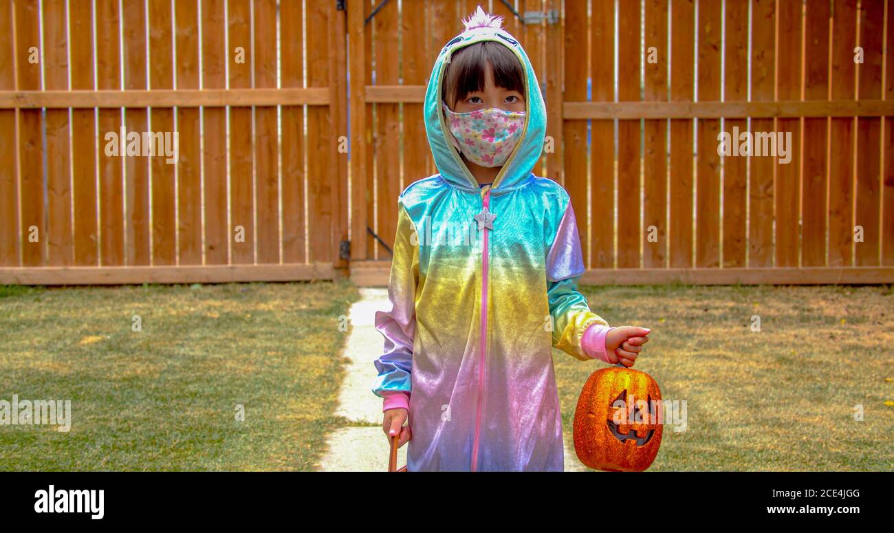 Ein Kindergärtner trägt eine Facemaske mit einem Kürbis Jack-o-Laterne während halloween während einer Pandemie. Konzept covid 19 während halloween. Stockfoto