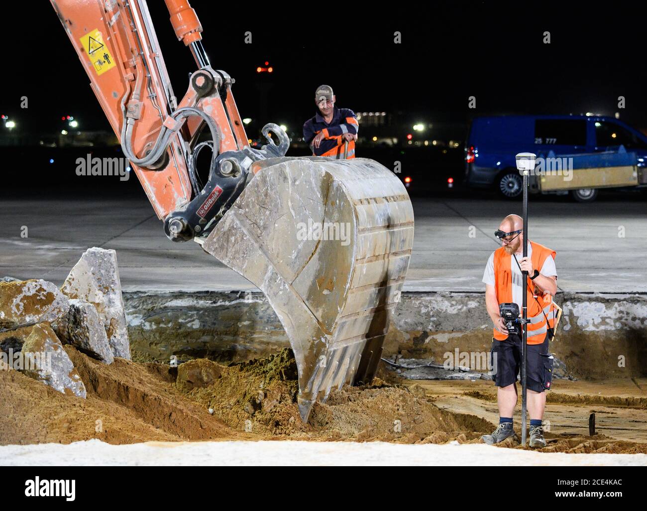 23. Juli 2020, Hessen, Frankfurt/Main: Ein Bauarbeiter steht mit einem Vermessungsinstrument in der Grube. Im Hintergrund steht ein Flugzeug auf seiner Parkposition. Für rund 35 Millionen Euro saniert die Fraport AG einen der wichtigsten Rollenbahnen in 250 Baunächten am Flughafen. Dies muss in Sektionen erfolgen, da nur die Nachtstunden für die Arbeiten zur Verfügung stehen und der sanierte Bereich bereits am nächsten Tag wieder einsatzbereit sein muss. Foto: Andreas Arnold/dpa Stockfoto