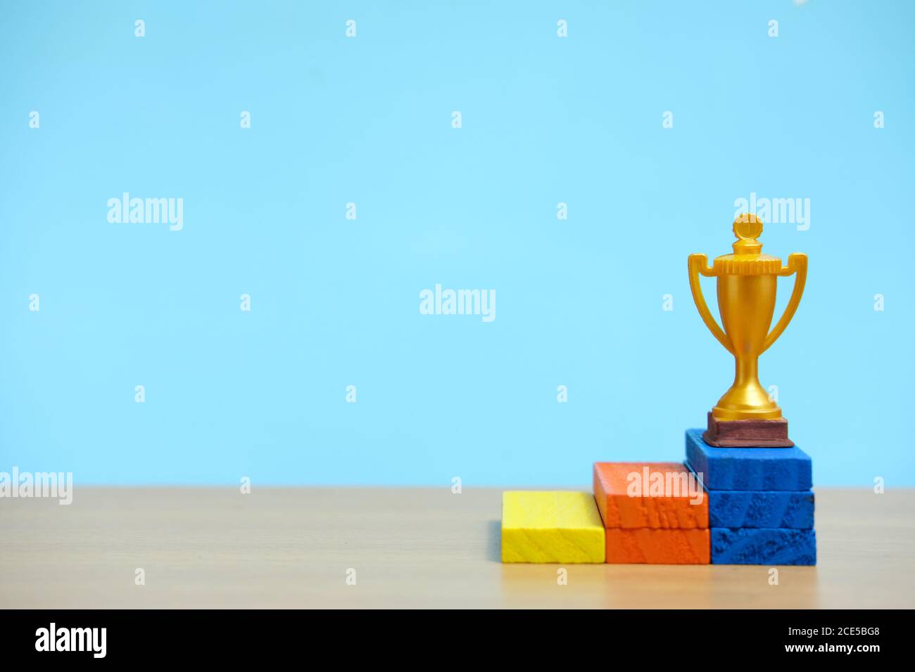 Goldene Trophäe auf buntem Podium auf Holztisch Stockfoto