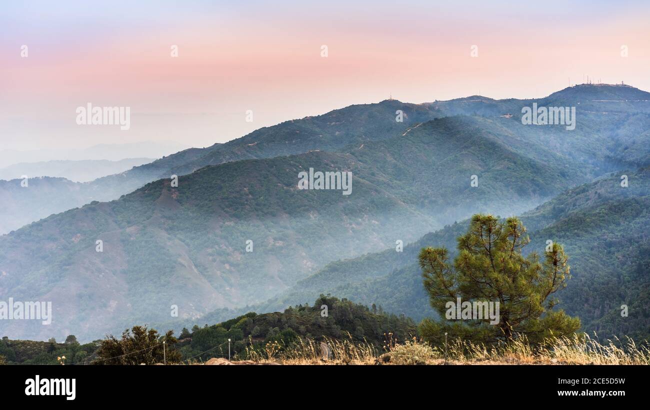 Blick auf den Sonnenuntergang in den Bergen von Santa Cruz; Rauch von den in der Nähe brennenden Waldbränden, sichtbar in der Luft und über den Bergkämmen und Tälern; Süden Stockfoto