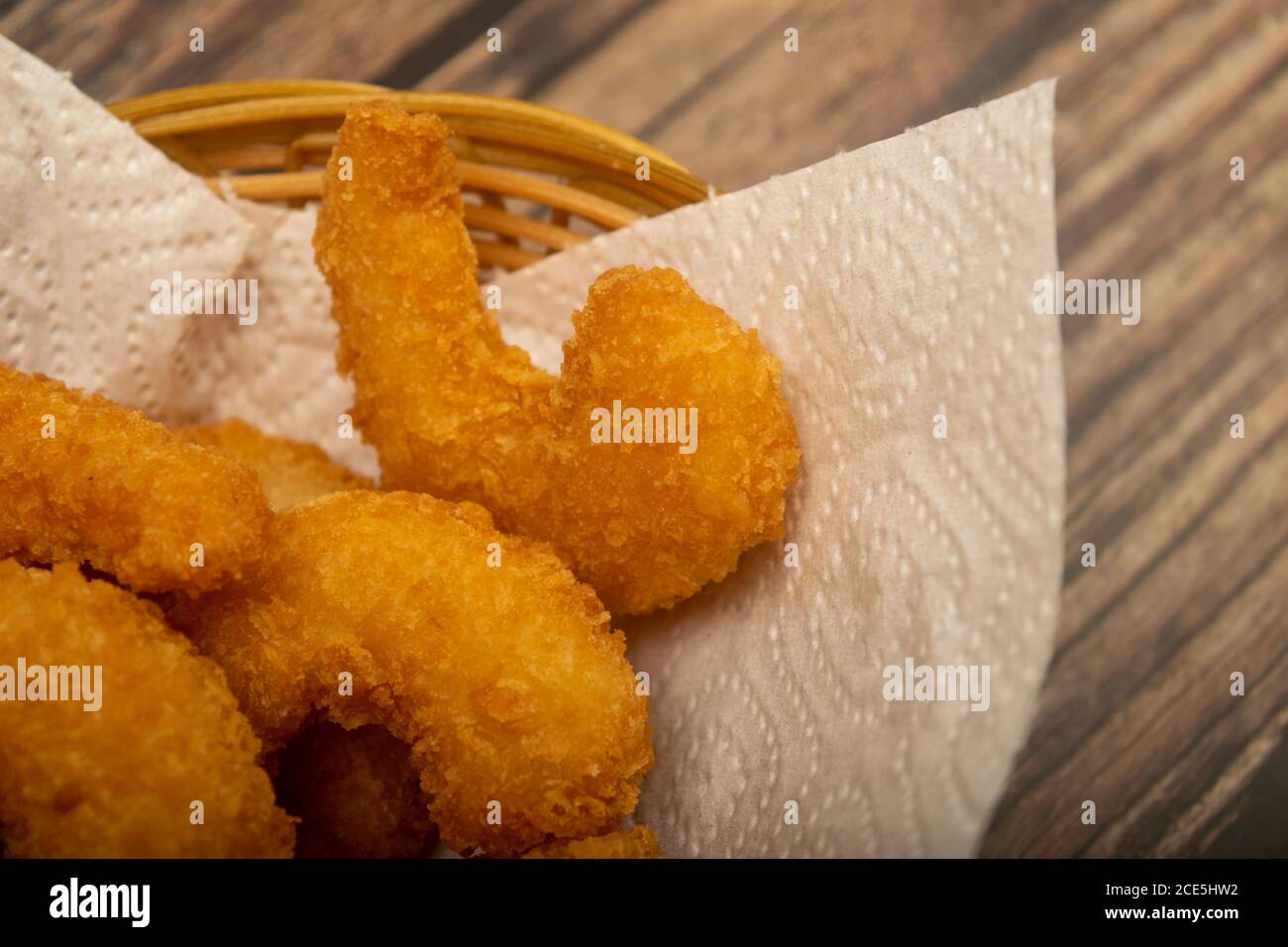 Atlantische Garnelen gebraten im Teig auf einer weißen Papierserviette in einem Weidenkorb. Nahaufnahme Stockfoto