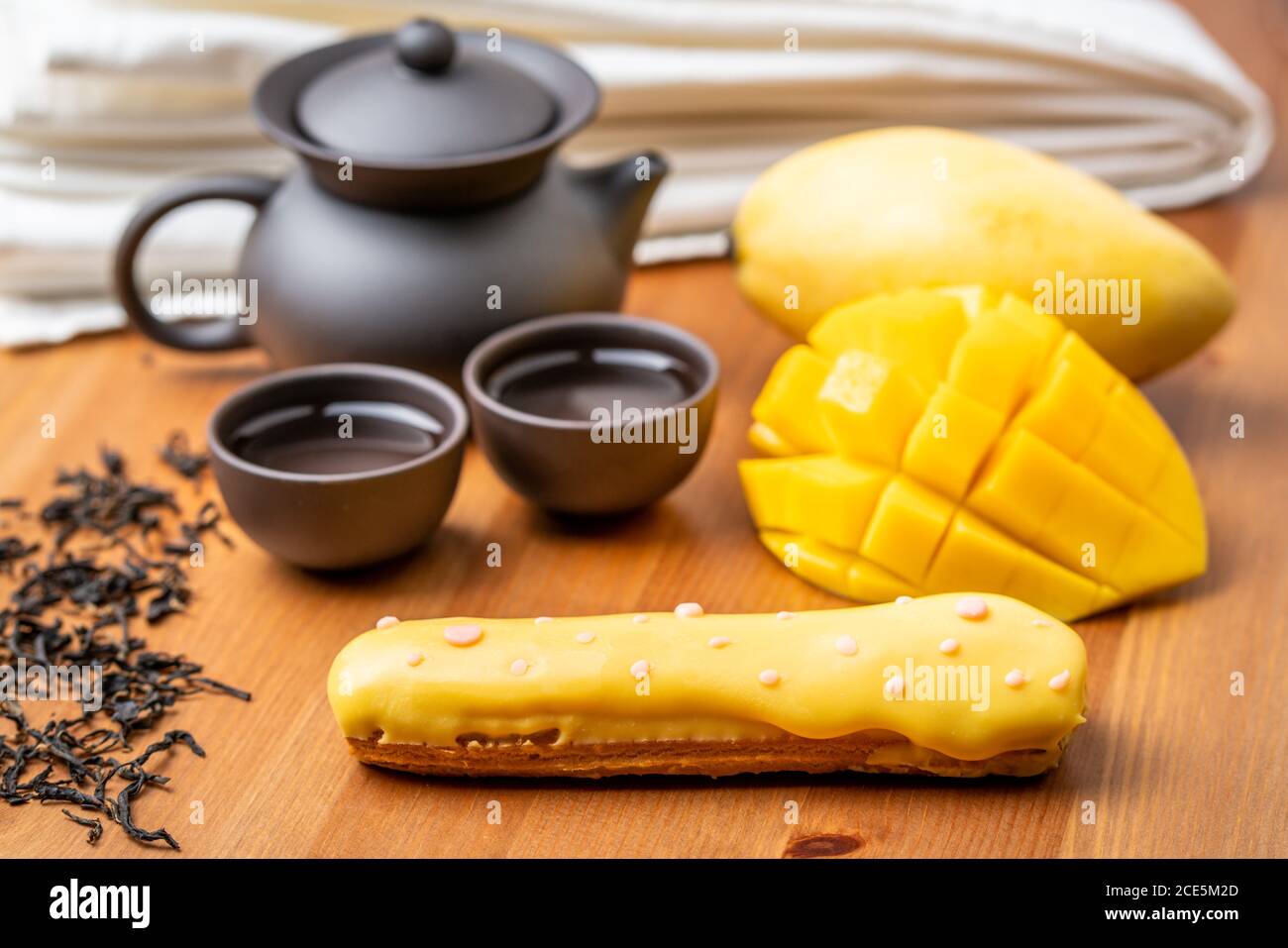 Eclair ein französisches Cremeteig mit Mango-Geschmack zeigt die Vollfrucht-Puff und Nachmittagstee-Set Stockfoto