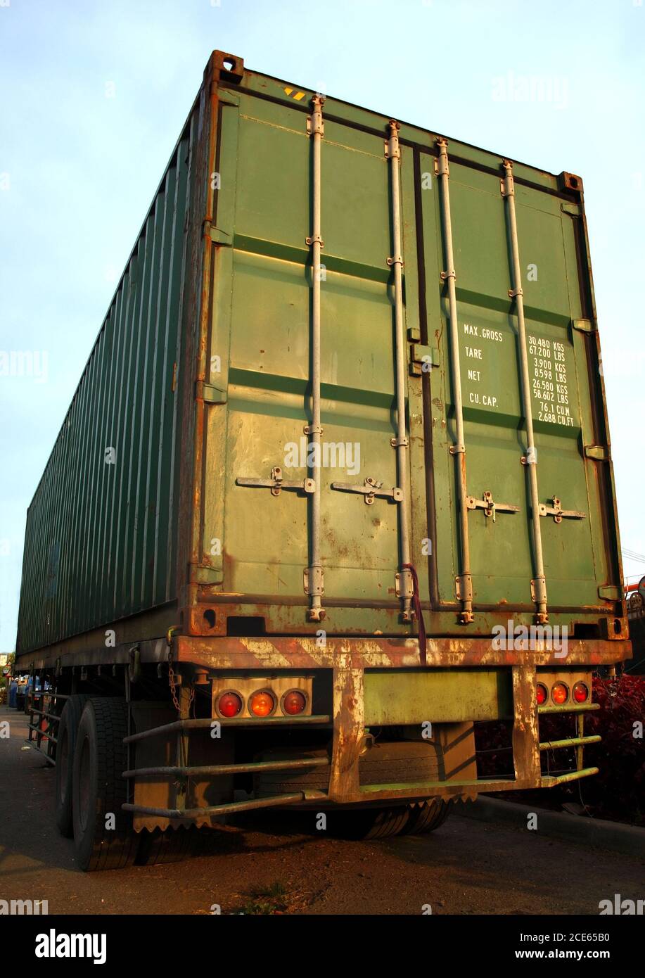Ein großer grüner Transportbehälter wird auf ein Flachbett geladen LKW Stockfoto
