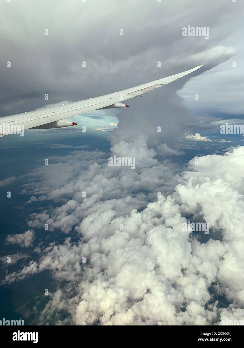 Flügel eines Flugzeugs, das über der extremen Wolke fliegt. Die Aussicht von einem Flugzeugfenster. Stockfoto